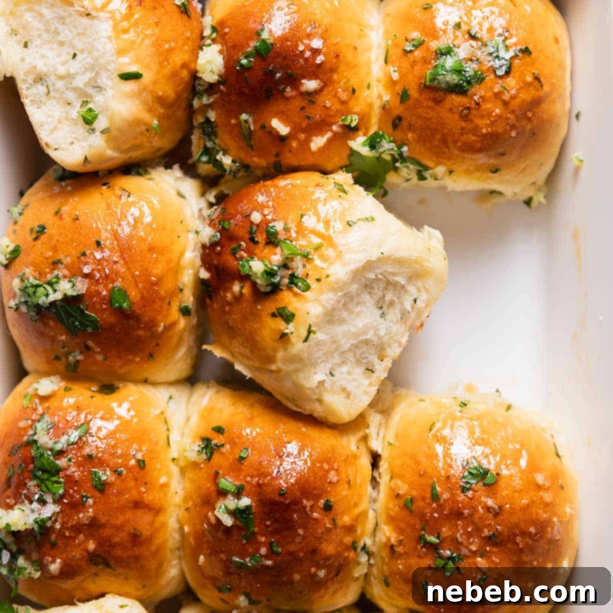 Garlic rolls brushed with garlic herb butter in a baking pan.