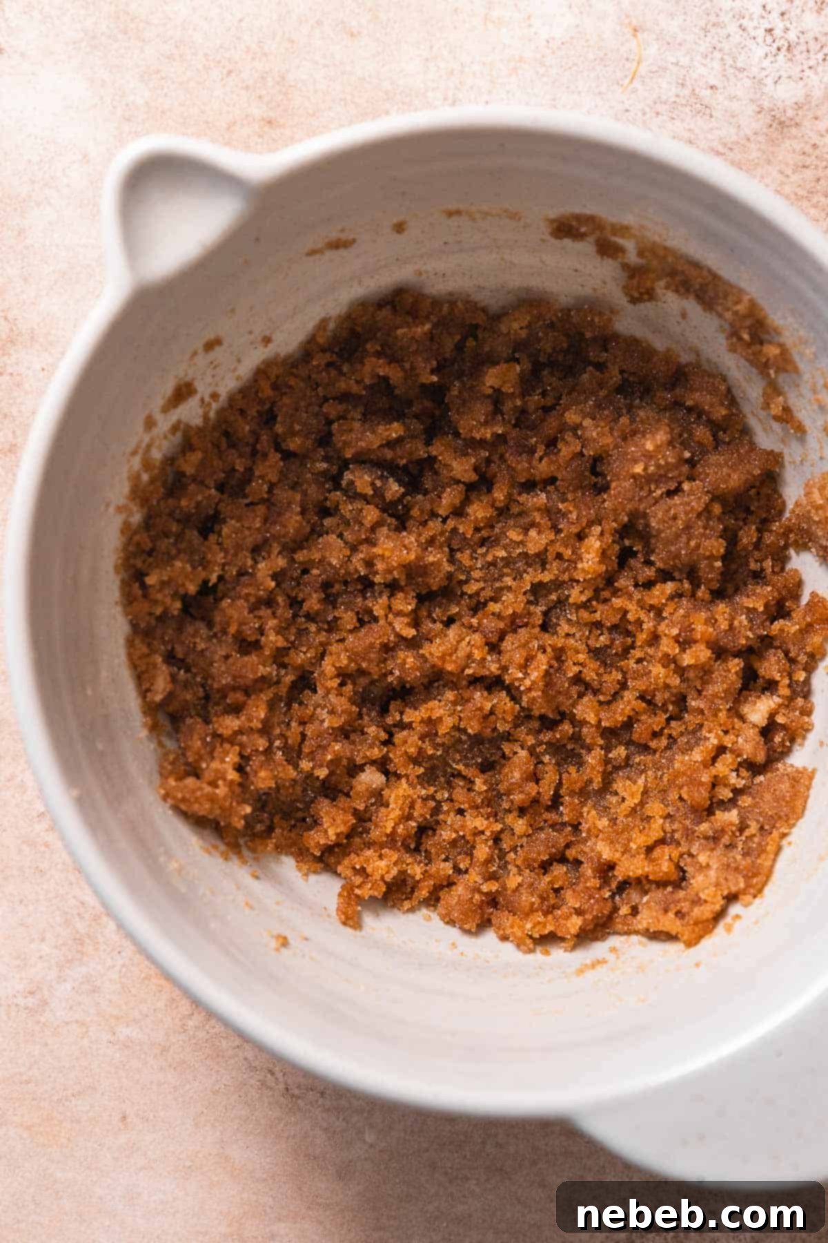 A mixing bowl containing thoroughly whisked brown butter and both granulated and dark brown sugars, creating a smooth, rich base for the cookie dough.