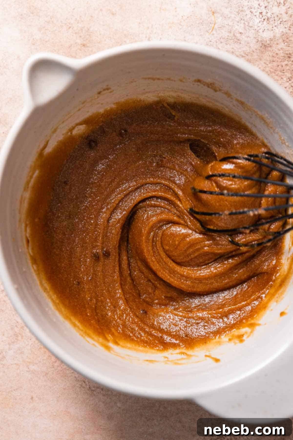 A mixing bowl filled with the wet ingredients: creamed brown butter, sugars, molasses, egg, and vanilla extract, all whisked together into a smooth, dark mixture.