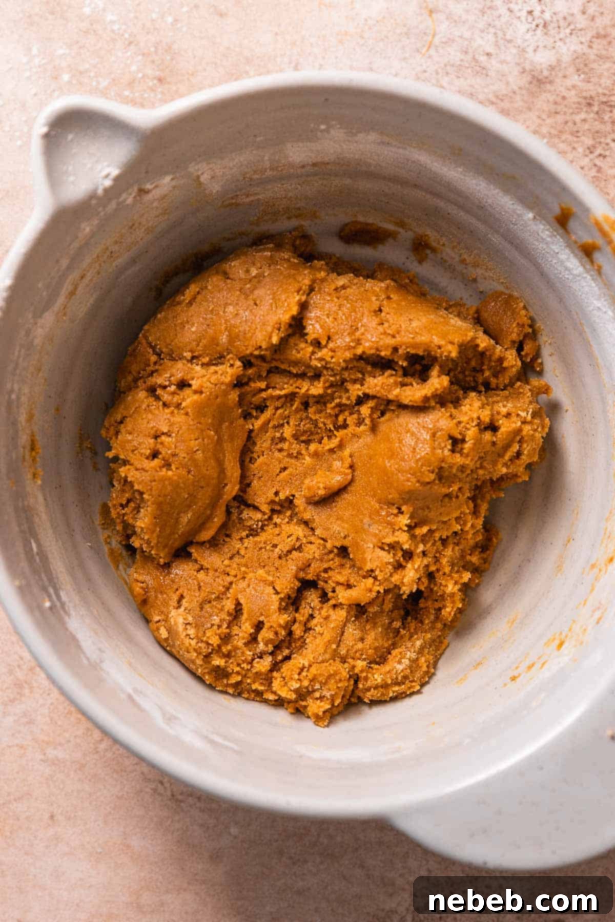 A mixing bowl filled with the molasses cookie dough, rich brown in color and perfectly textured before being scooped for chilling.