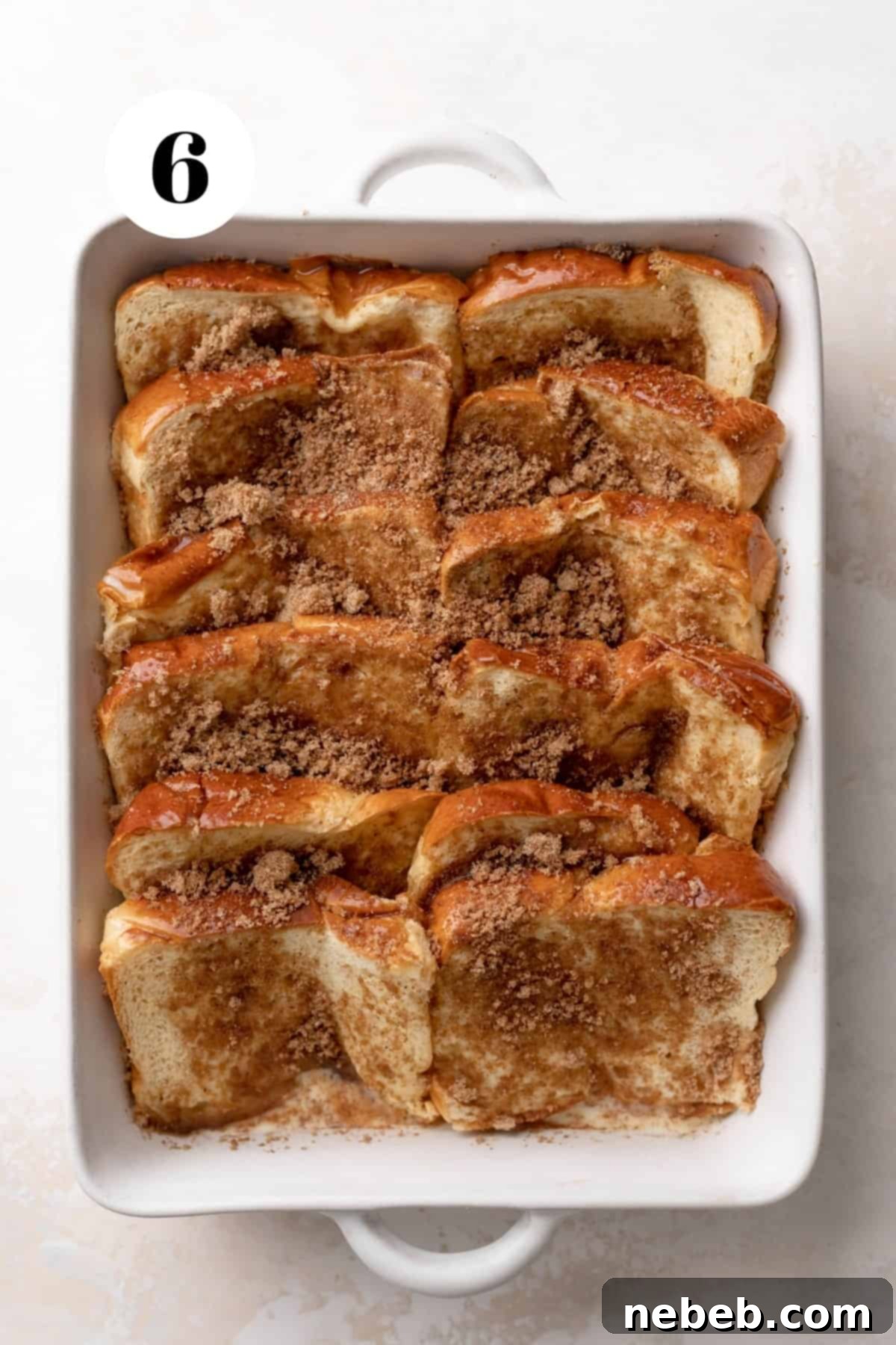Brioche french toast casserole covered with cinnamon sugar and ready to be chilled and baked.