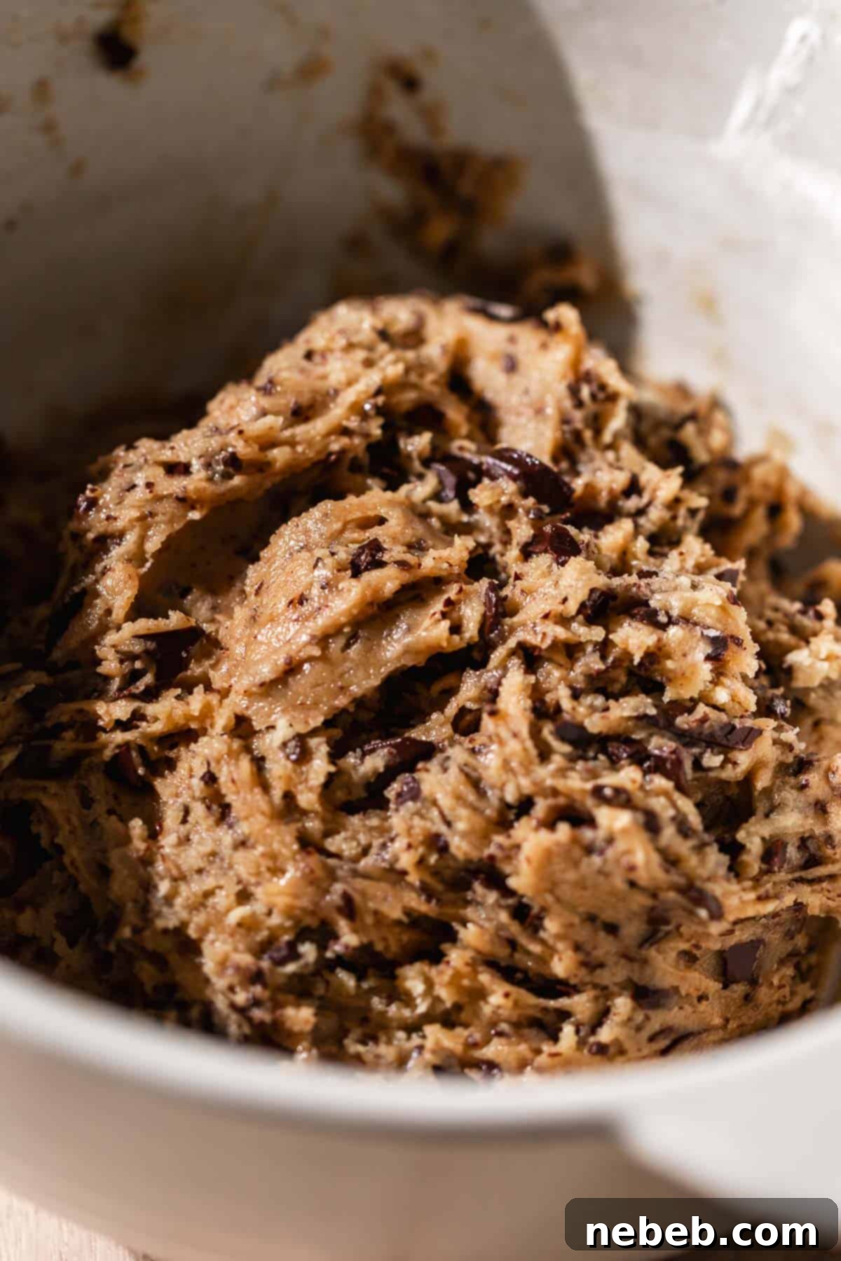 A large mixing bowl containing freshly prepared chocolate chip cookie dough, after all dry ingredients and chocolate chips have been gently folded in.