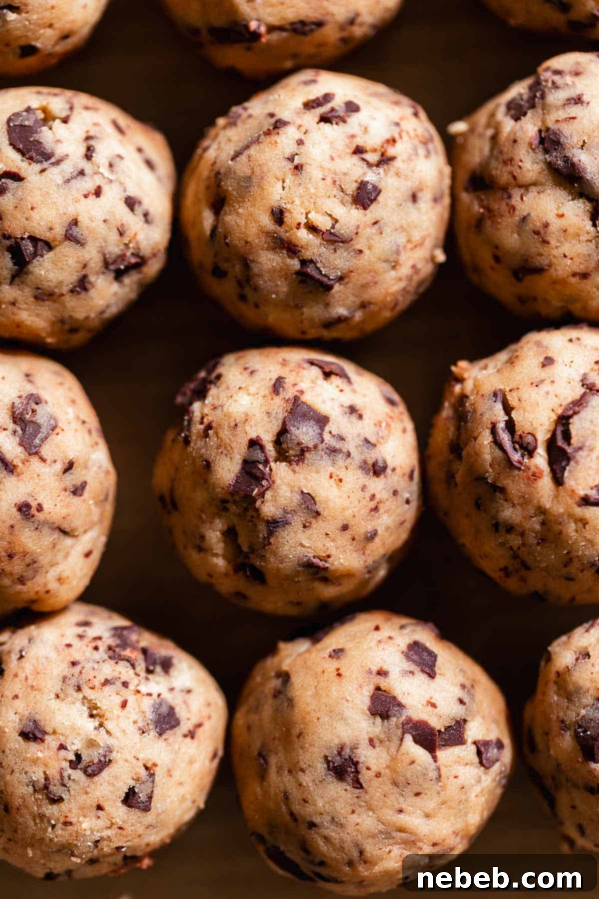 Rows of perfectly portioned and chocolate-stuffed cookie dough balls arranged on a baking tray, ready for chilling and baking.