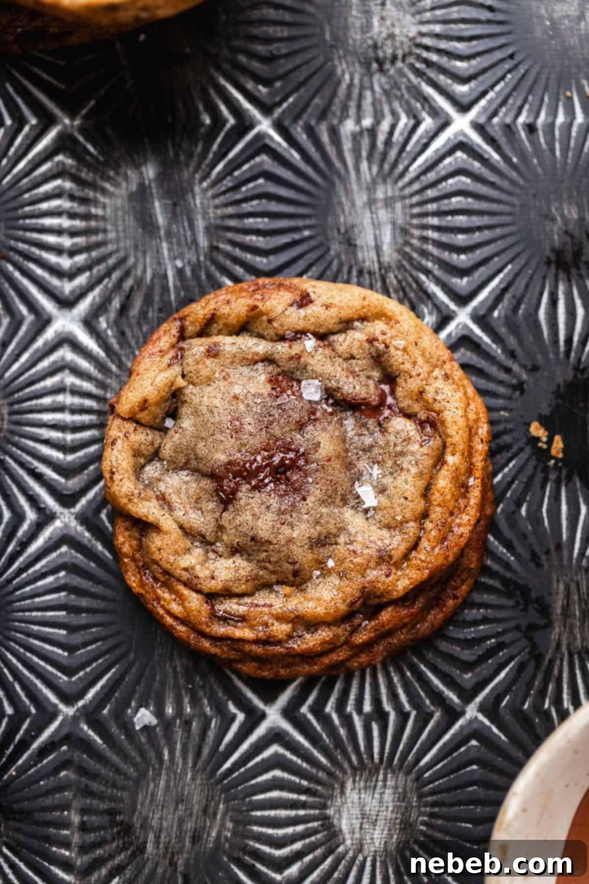 A single, perfectly baked chocolate hazelnut filled cookie resting on a dark baking pan, showing its slightly golden edges and irresistible center.