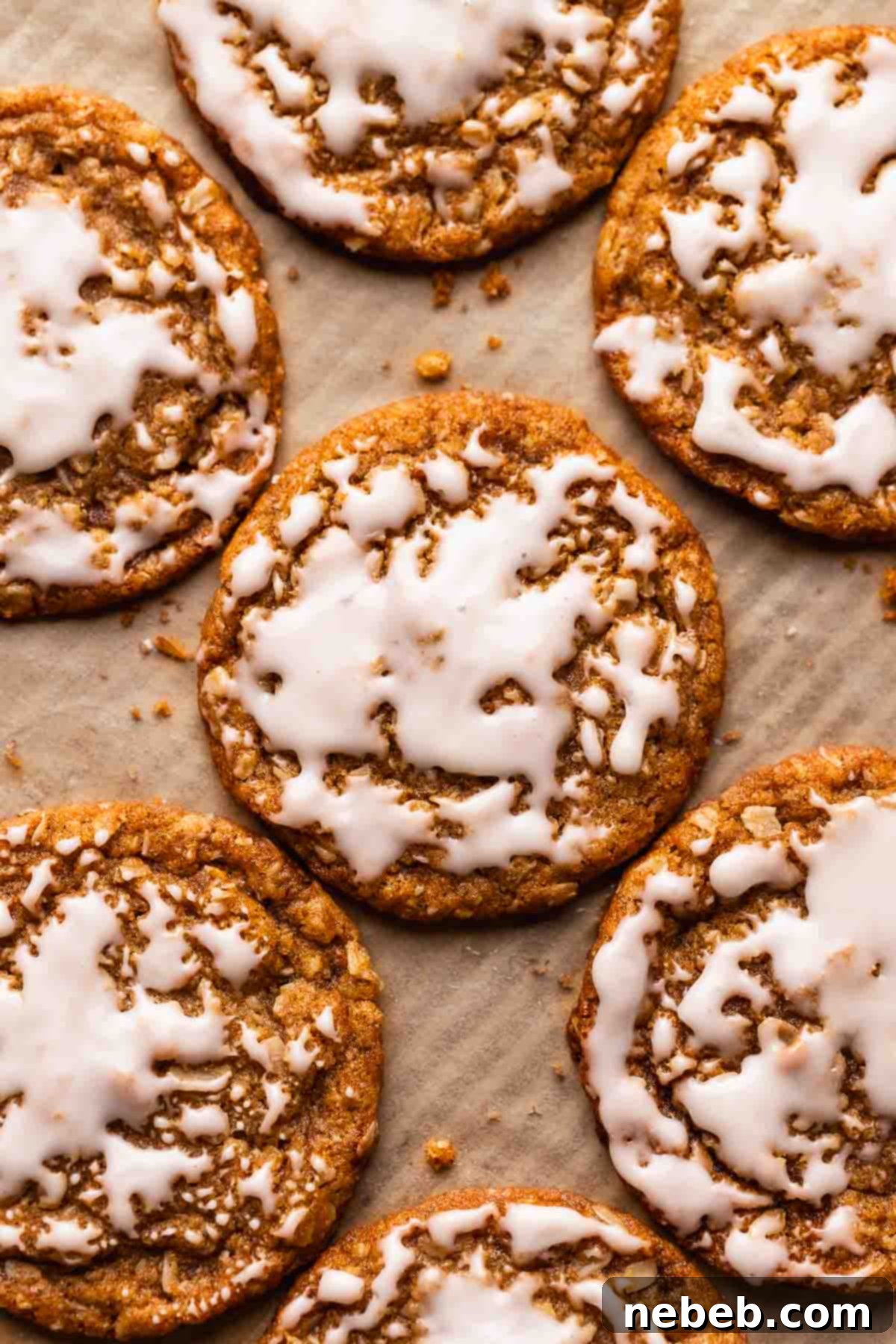Soft and chewy iced oatmeal cookies arranged beautifully on a brown parchment paper lined baking tray, freshly glazed.