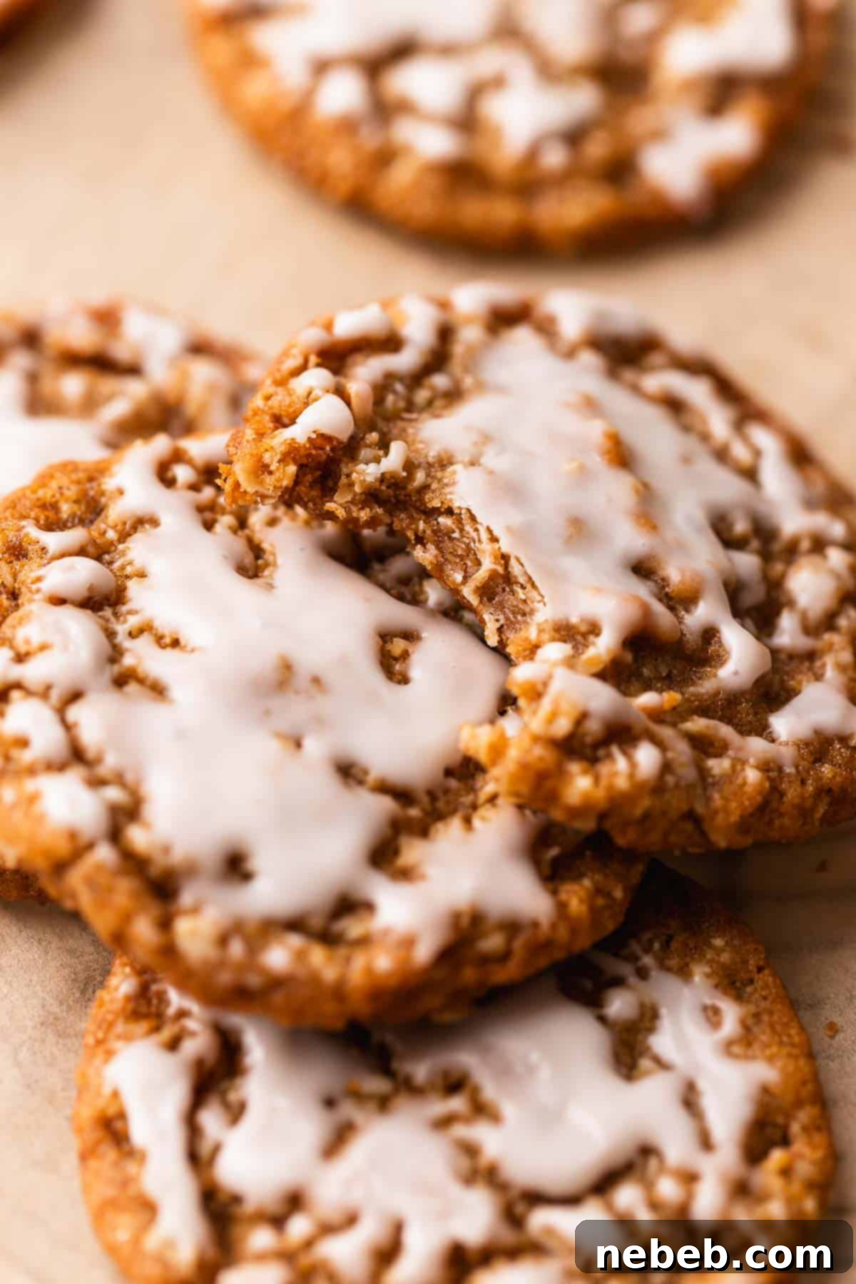 A frosted oatmeal cookie with a bite taken out of it, clearly showing the wonderfully chewy and soft texture of the interior.