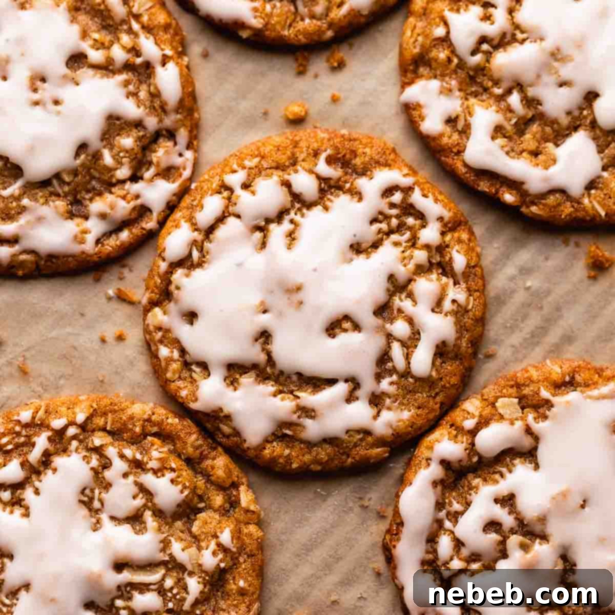 Oatmeal cookies with icing on a parchment lined baking tray, ready to be enjoyed.