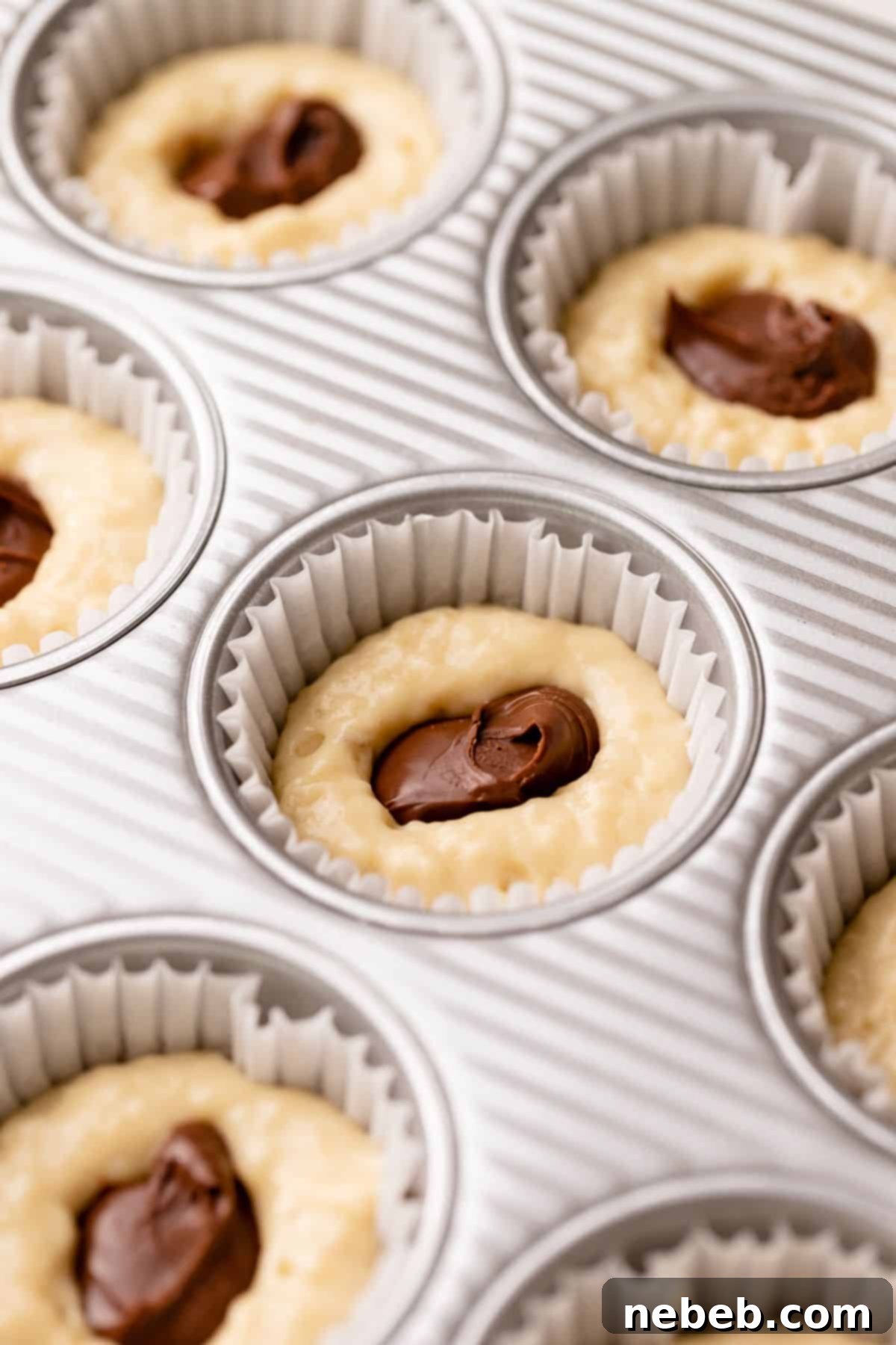 Nutella Swirl Banana Muffins 8 Muffins being stuffed with scoops of nutella spread.