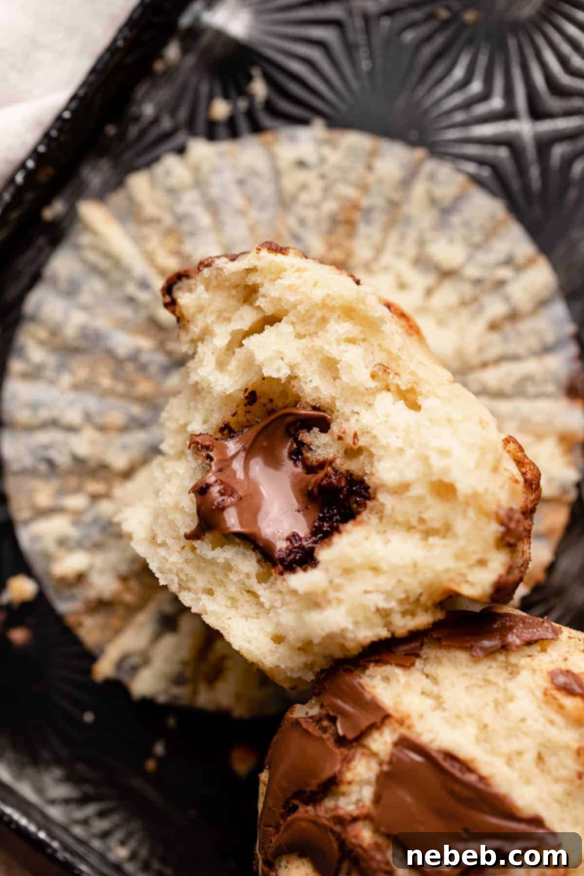 Nutella Swirl Banana Muffins 10 a nutella muffin cut in half to show the gooey chocolate hazelnut spread in the center.
