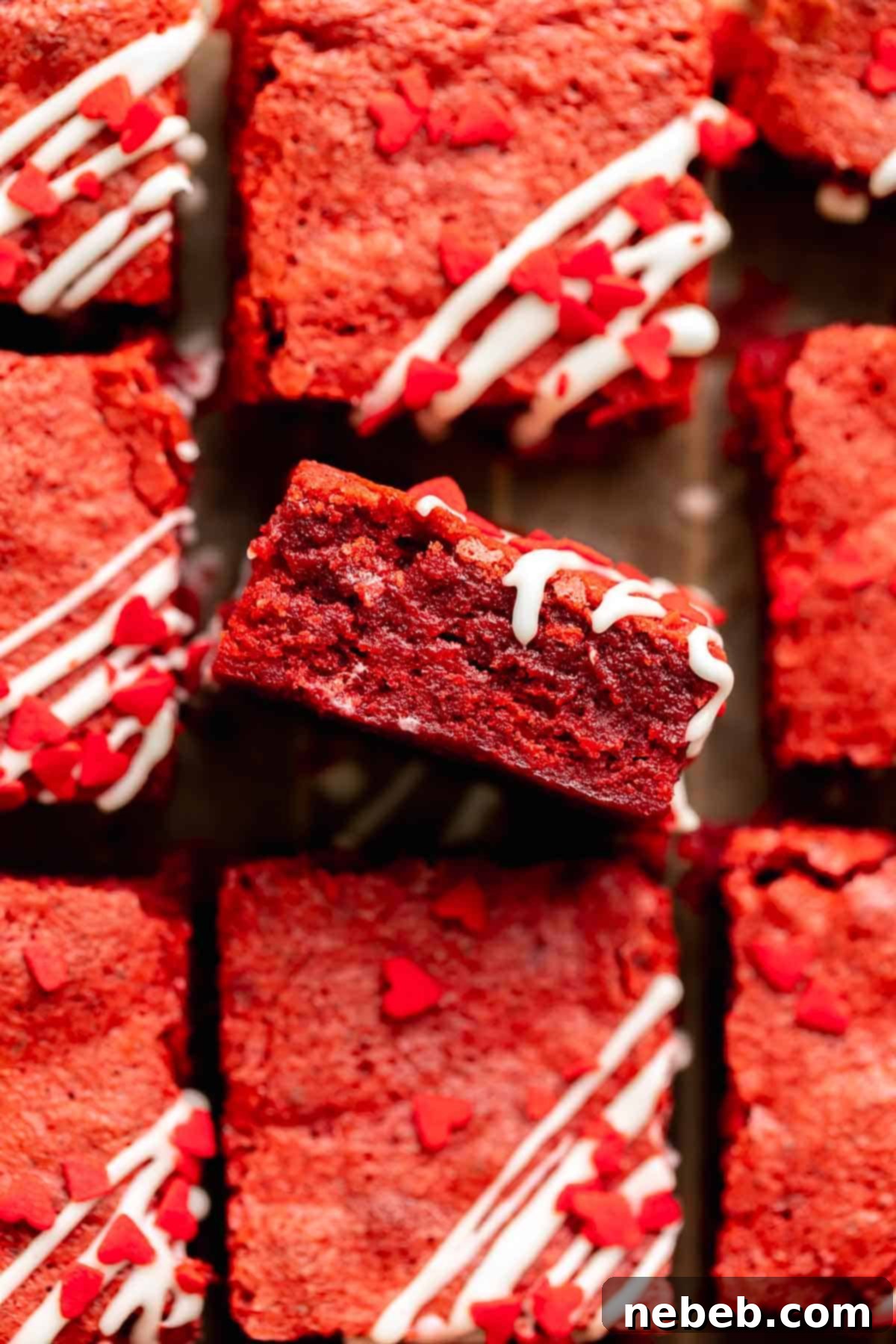 Red velvet brownie facing up to show the fudgy brownie texture, topped with cream cheese drizzle and heart sprinkles.
