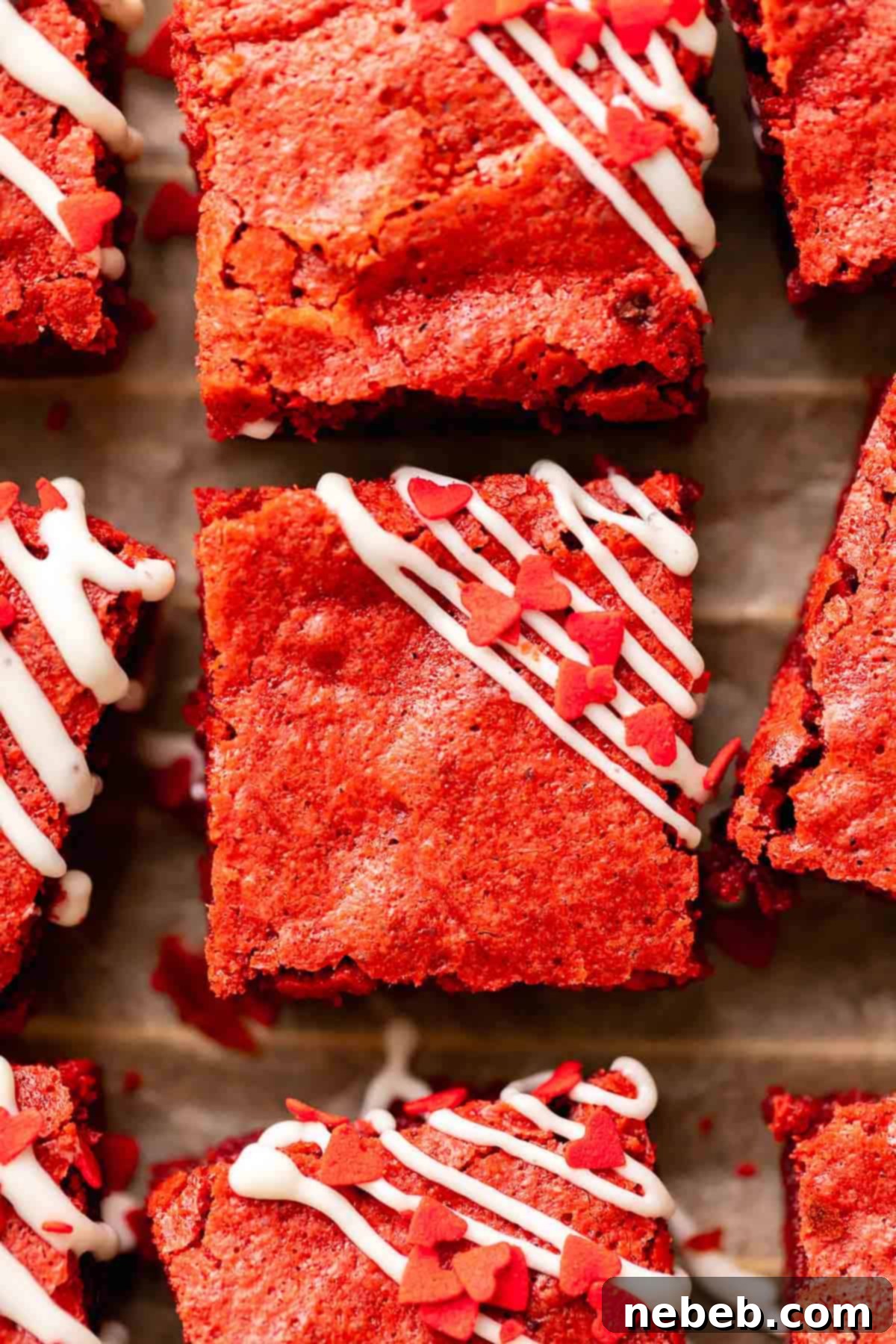 Red velvet brownies drizzled with cream cheese icing and sprinkled with heart sprinkles, ready to serve.
