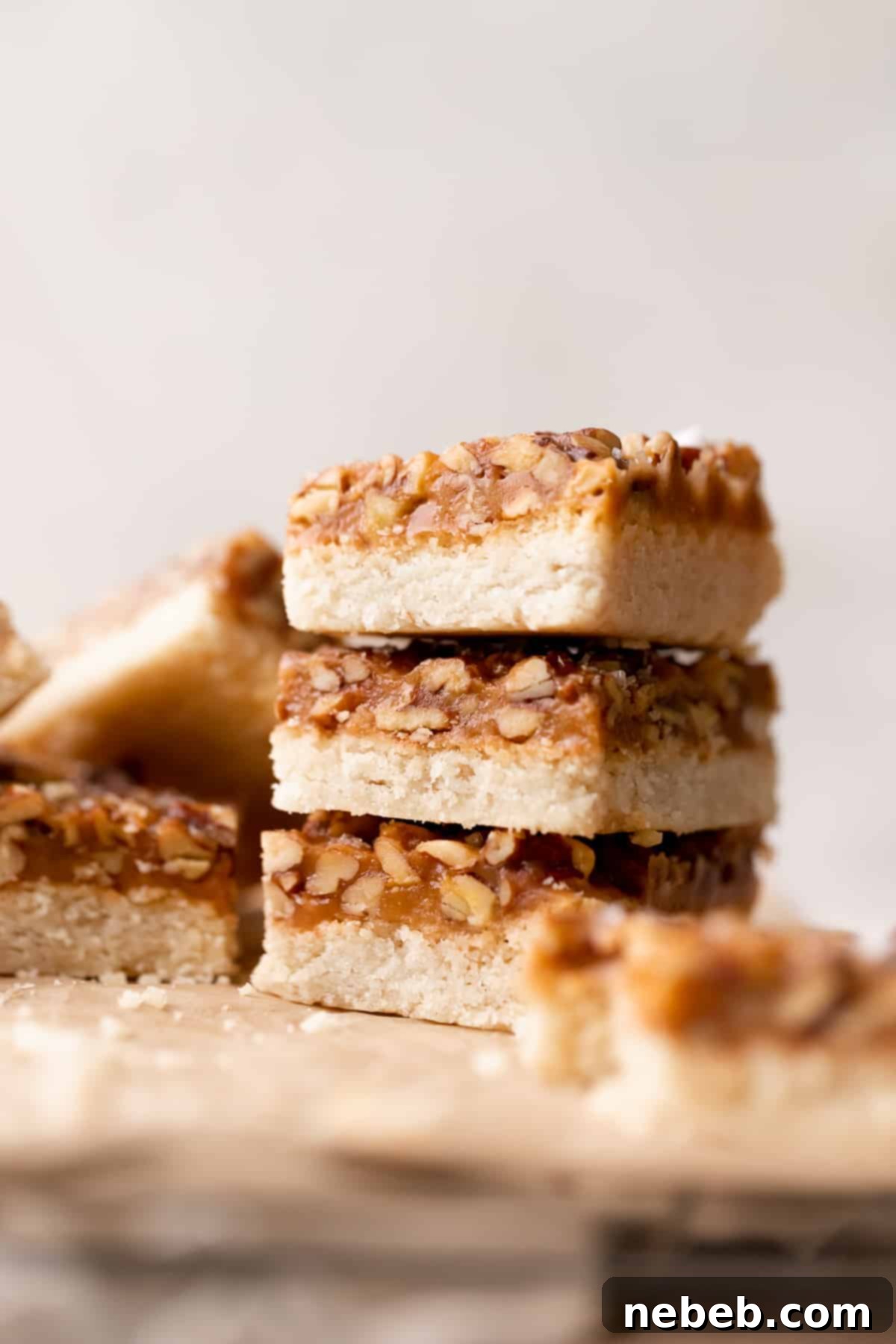 three caramel pecan bars stacked on top of each other.