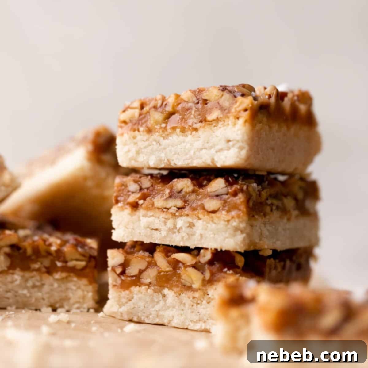 caramel pecan bars in a stack on parchment paper.