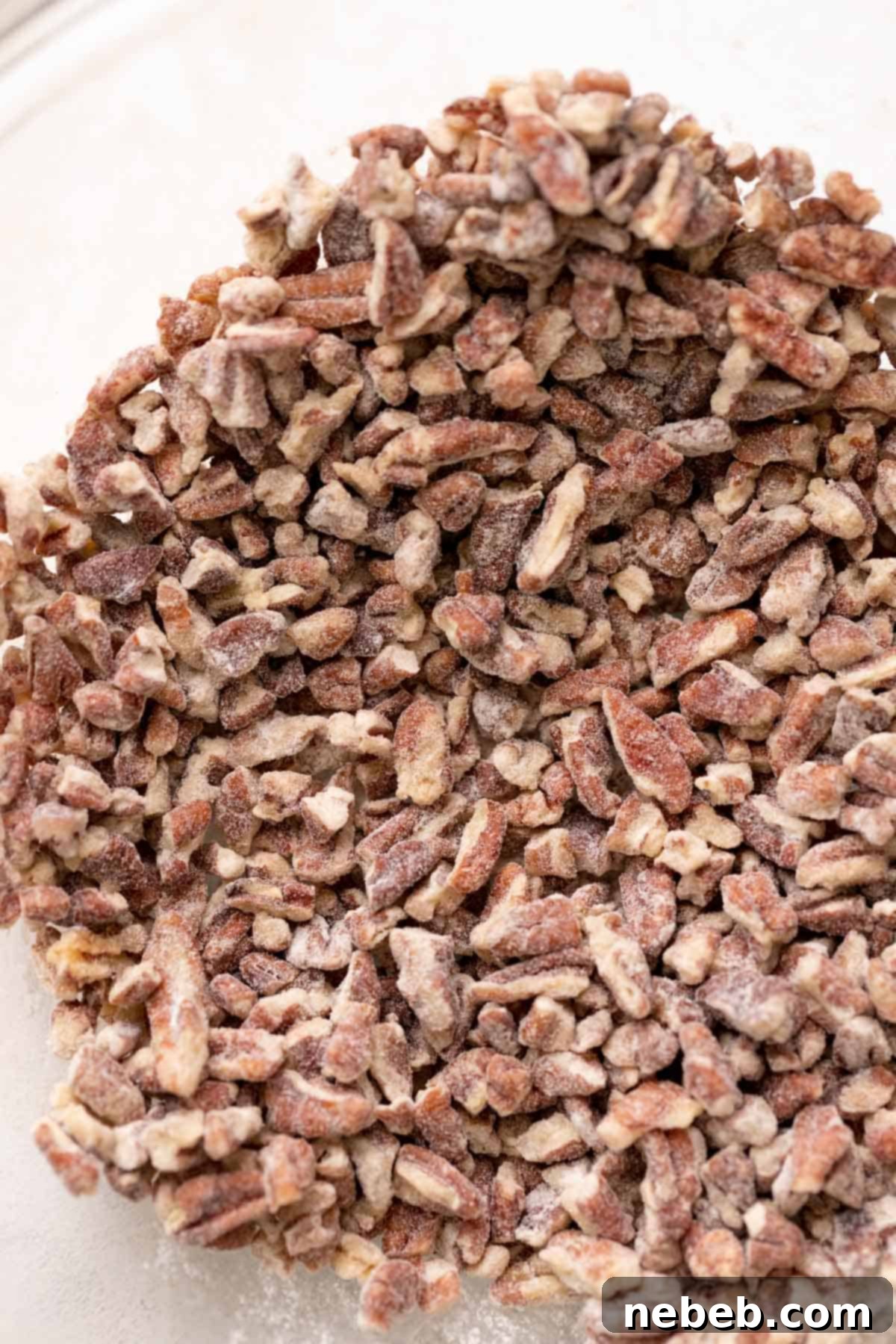 a bowl of pecans that have been tossed in flour.