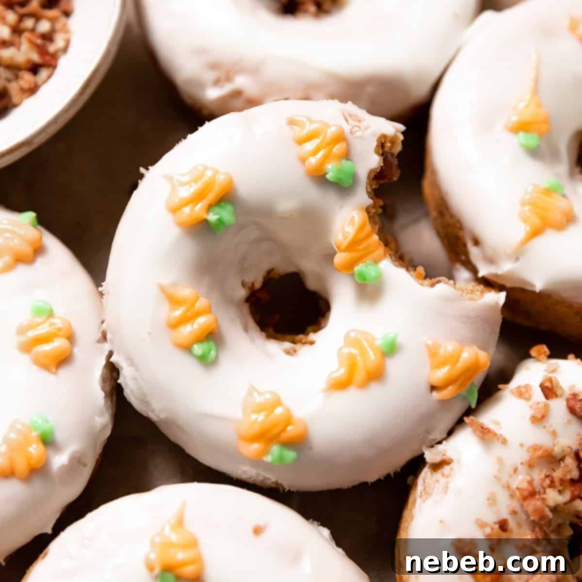 carrot cake donuts topped with cream cheese icing and candied pecans, beautifully presented.