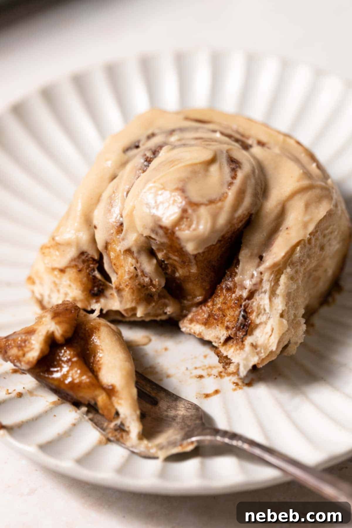 coffee roll on a plate with a bite on a fork.