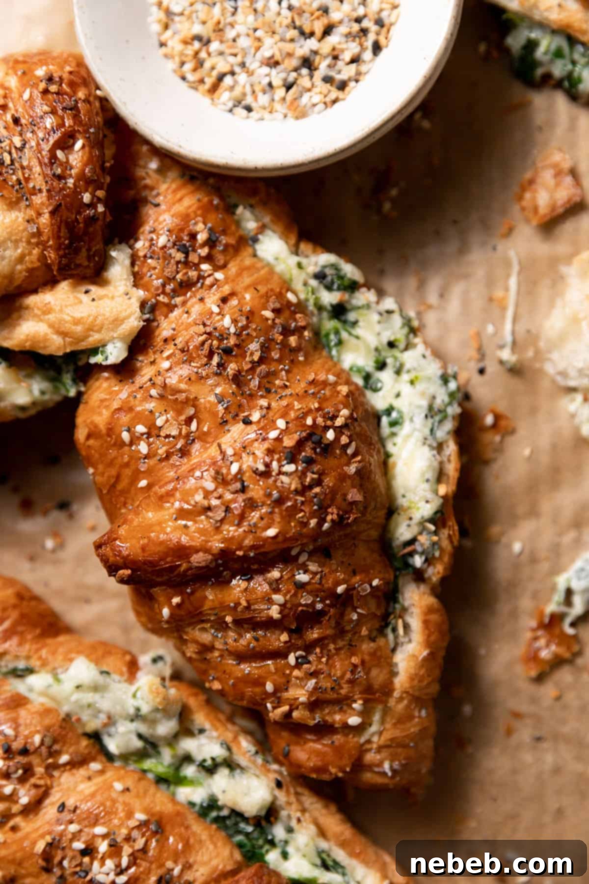 Two golden-brown spinach croissants generously topped with everything bagel seasoning, ready to be enjoyed.