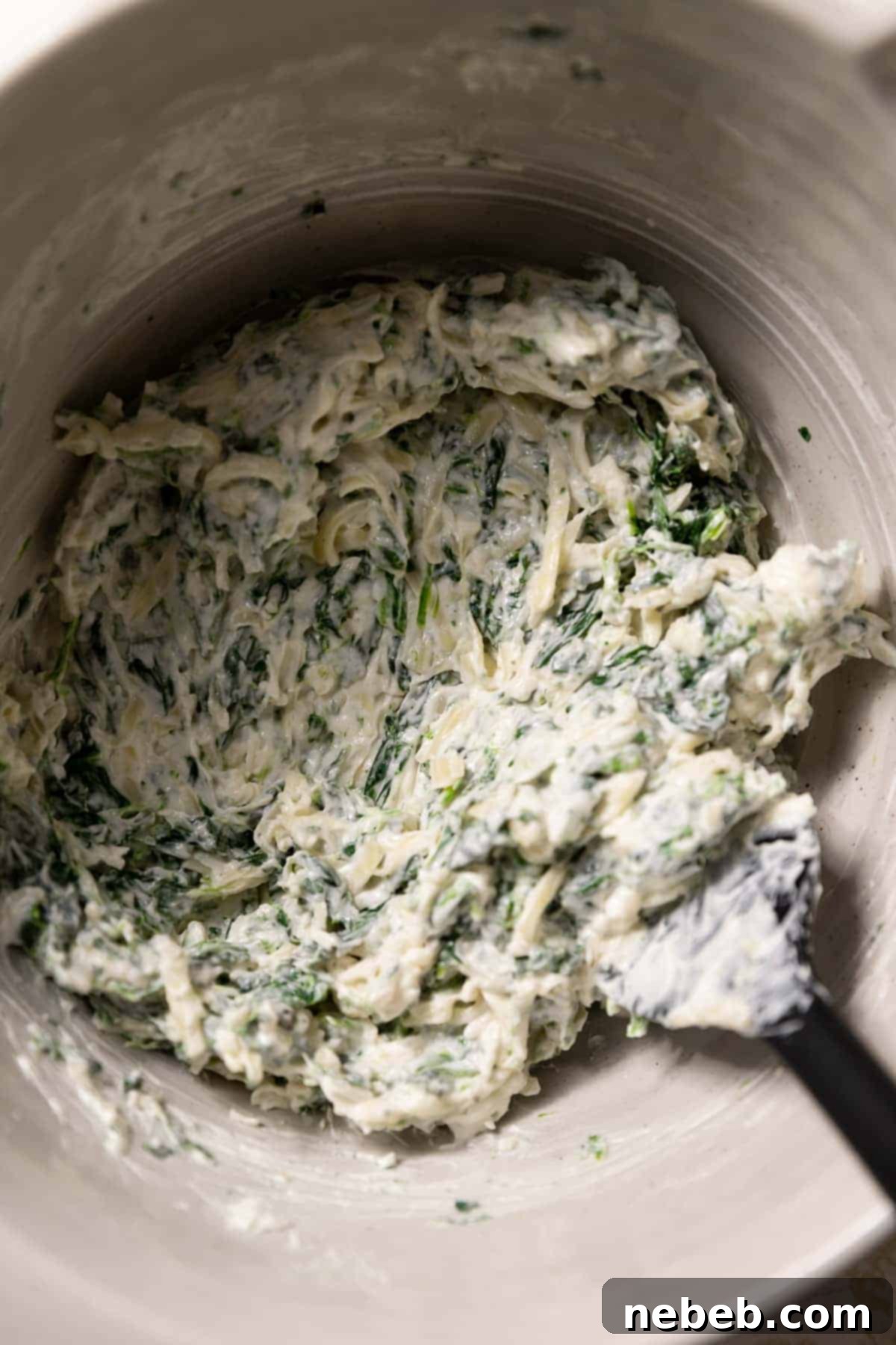 A mixing bowl filled with creamy spinach, mozzarella, cream cheese, and spices, ready to be stuffed into croissants.