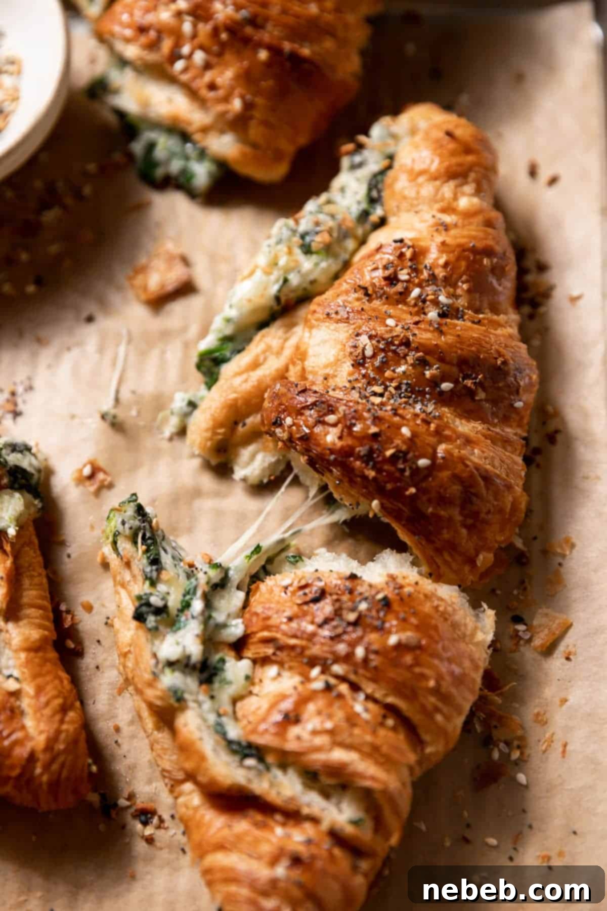 A freshly baked, golden spinach croissant, with its cheesy filling perfectly melted and visible.