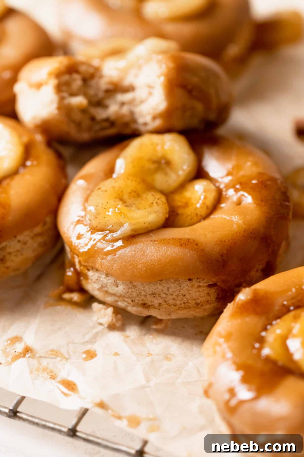 Baked banana donuts with brown sugar glaze and bananas on top, showcasing their moist texture.