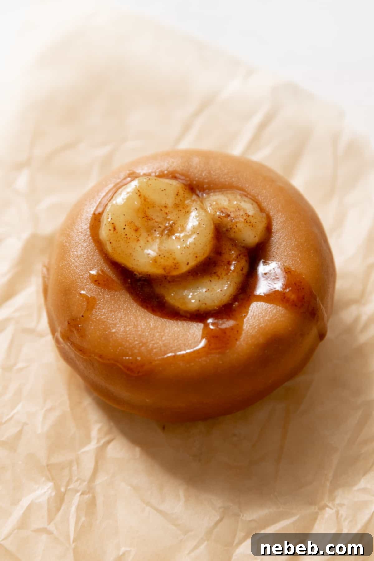 A freshly baked banana donut resting on brown parchment paper, ready for glazing.