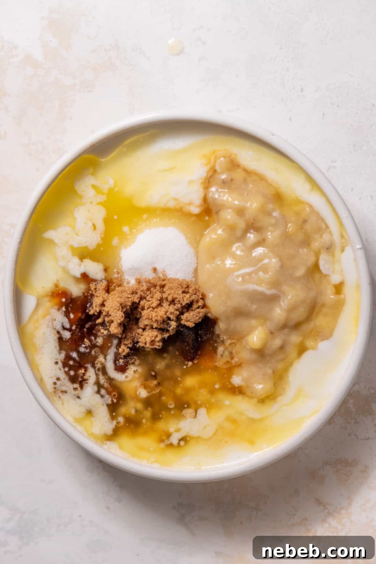 Whisking together the wet ingredients, including mashed banana and melted butter, in a separate mixing bowl.