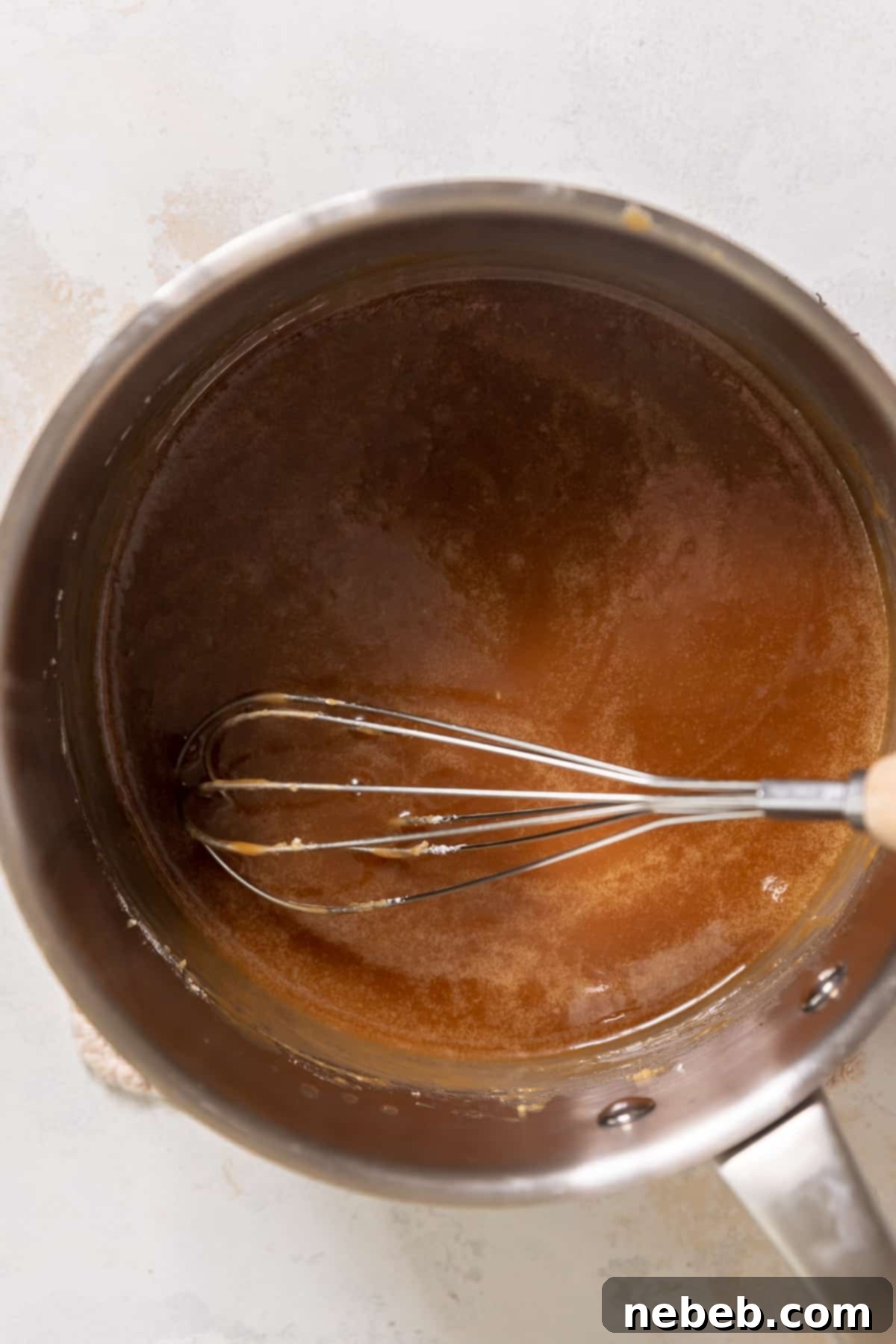 Brown sugar glaze simmering in a pot on the stovetop, thickening as it cools.