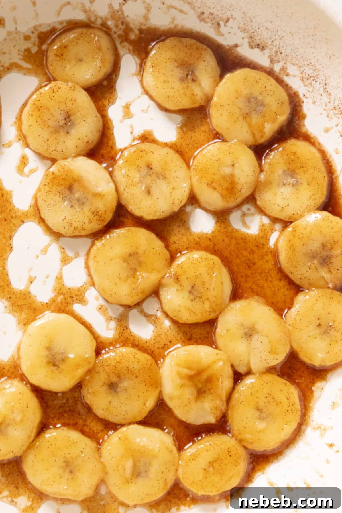 Caramelized banana slices being prepared in a pan, glistening with brown sugar and butter.