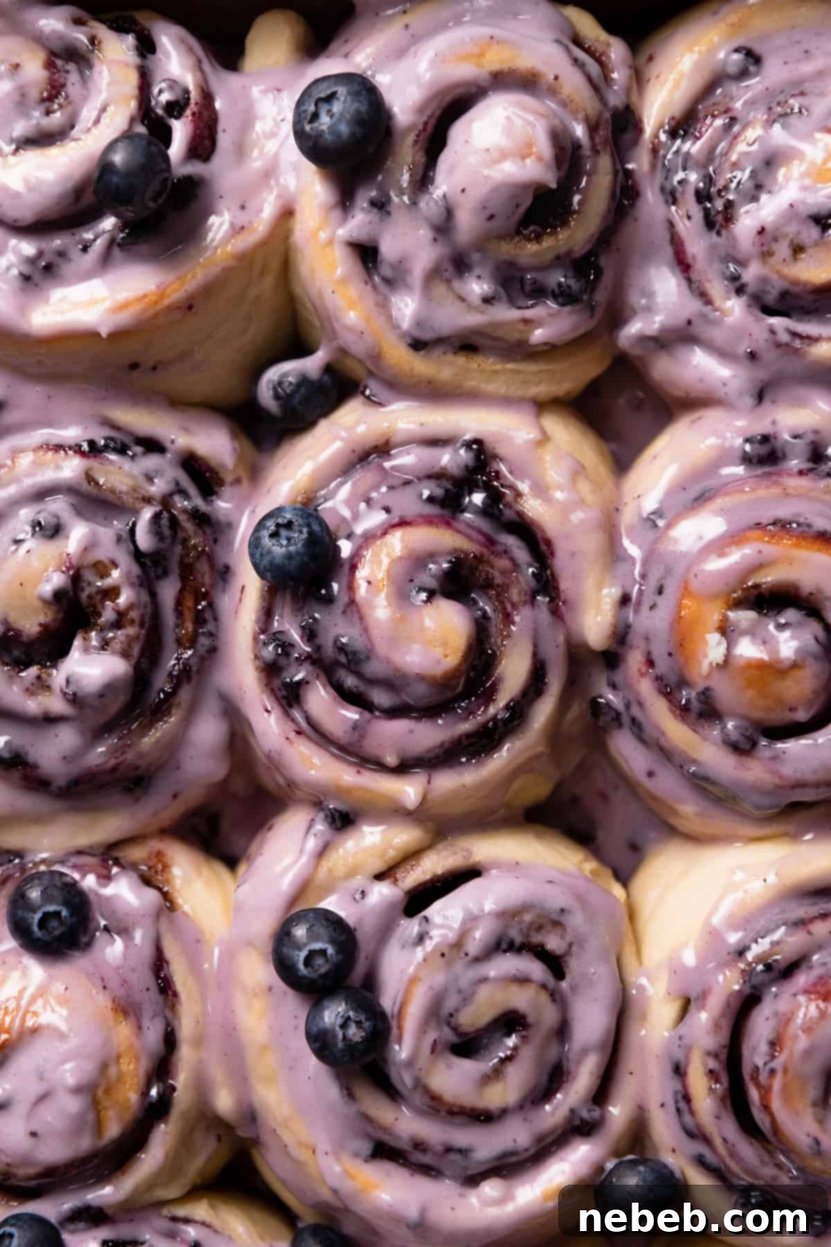 Gooey blueberry cinnamon rolls covered in a thick layer of blueberry cream cheese frosting, ready to be enjoyed for breakfast or dessert.
