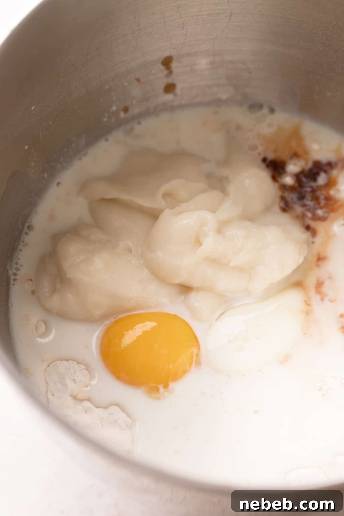 Wet and dry ingredients for cinnamon roll dough being mixed together in a stand mixer bowl.