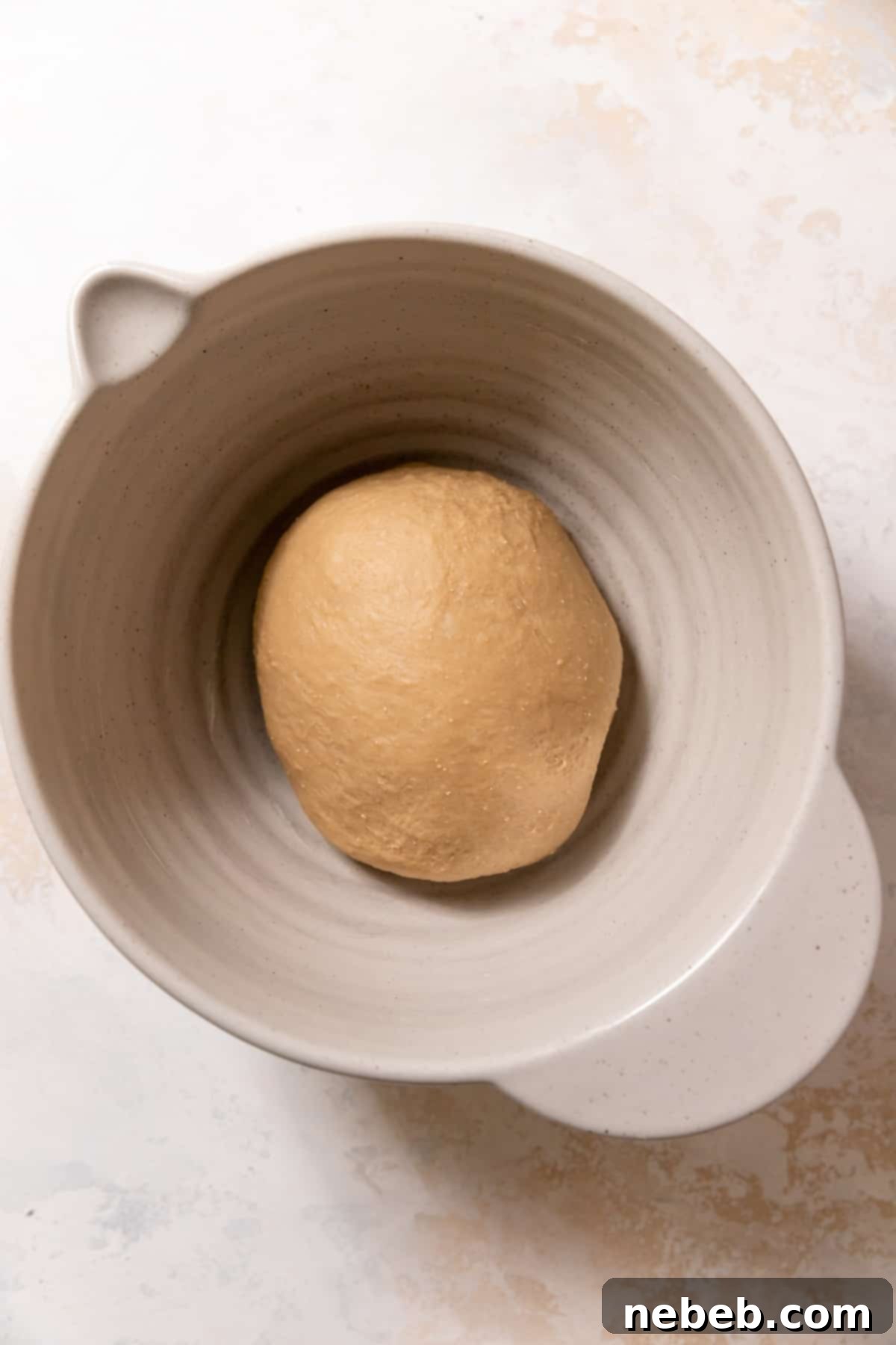 Smooth and elastic cinnamon roll dough resting in a bowl after kneading.