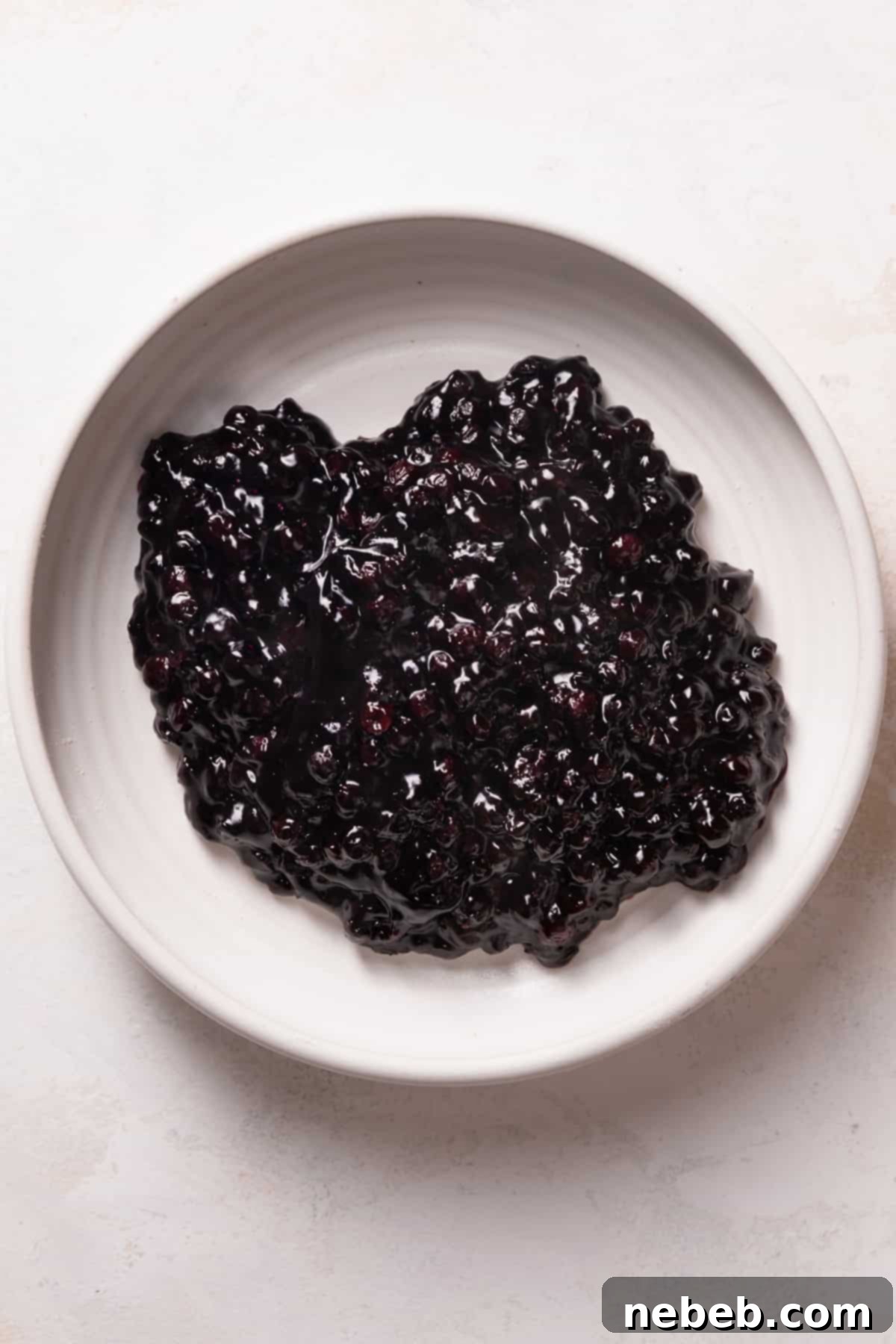 Thick, vibrant blueberry jam in a white bowl, ready for filling the cinnamon rolls.
