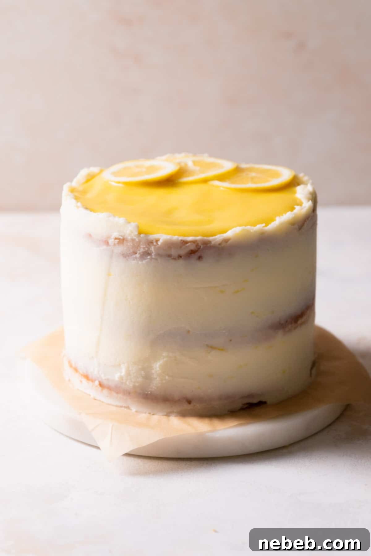 The fully decorated lemon bar cake, elegantly frosted with cream cheese buttercream and topped with fresh lemon curd, on a white marble slab.