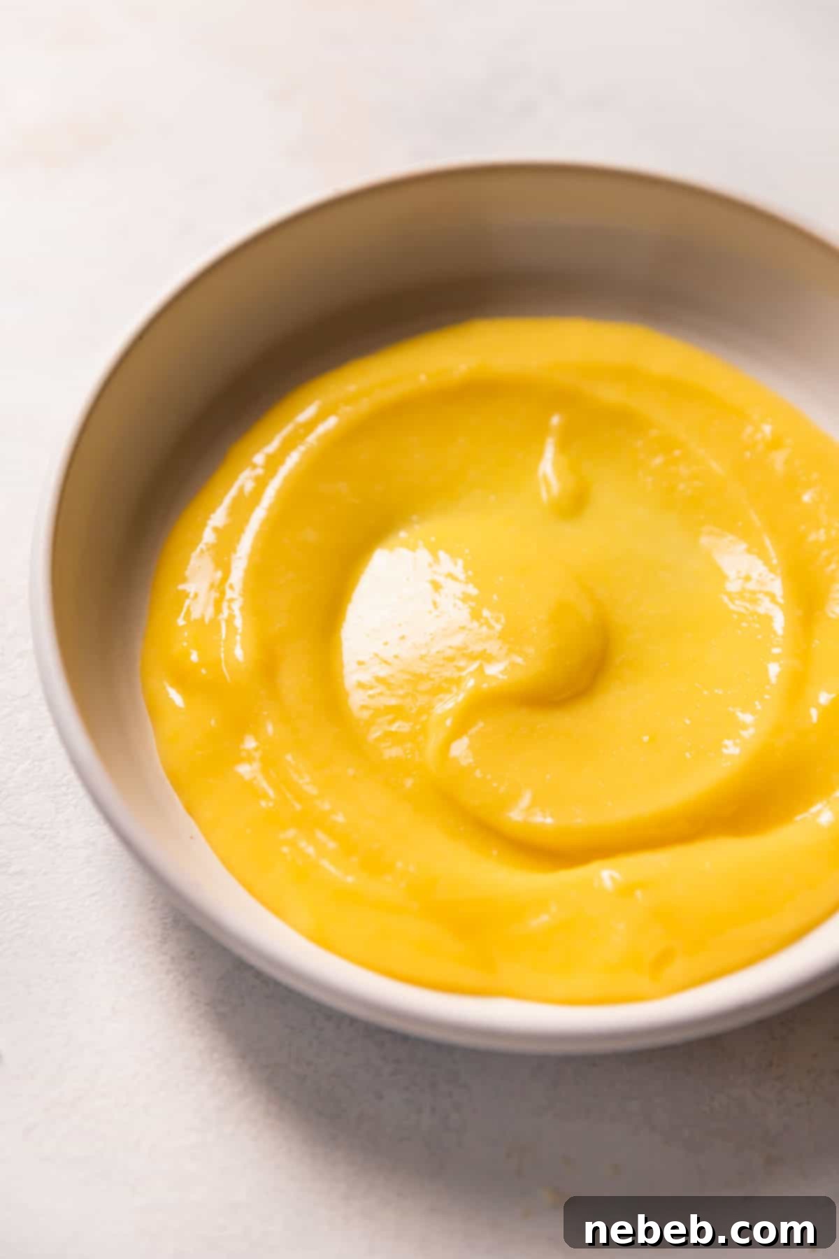 A bowl of vibrant, freshly made lemon curd, smooth and glossy, ready for the next step of the cake.
