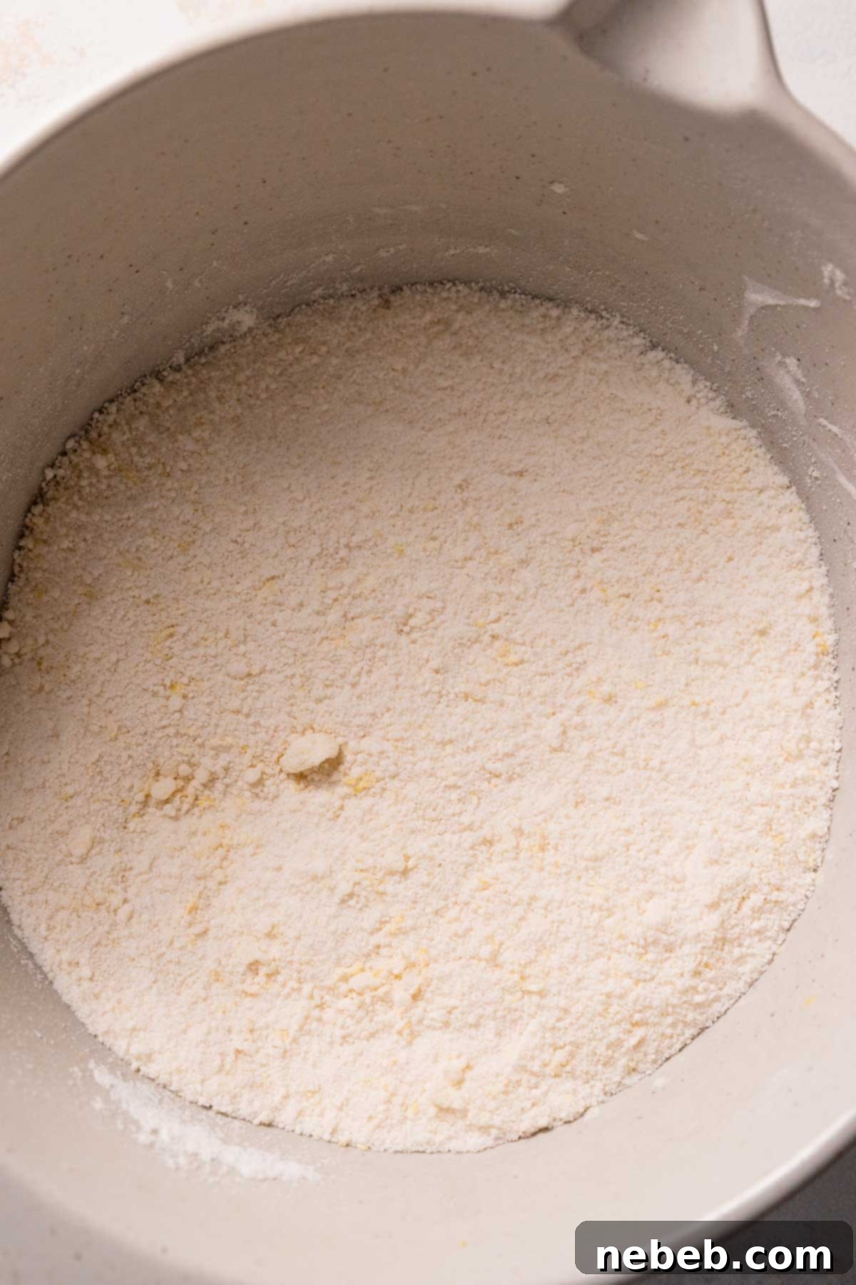 Dry ingredients and room temperature butter are partially mixed in a stand mixer bowl, showing a crumbly texture before wet ingredients are added.