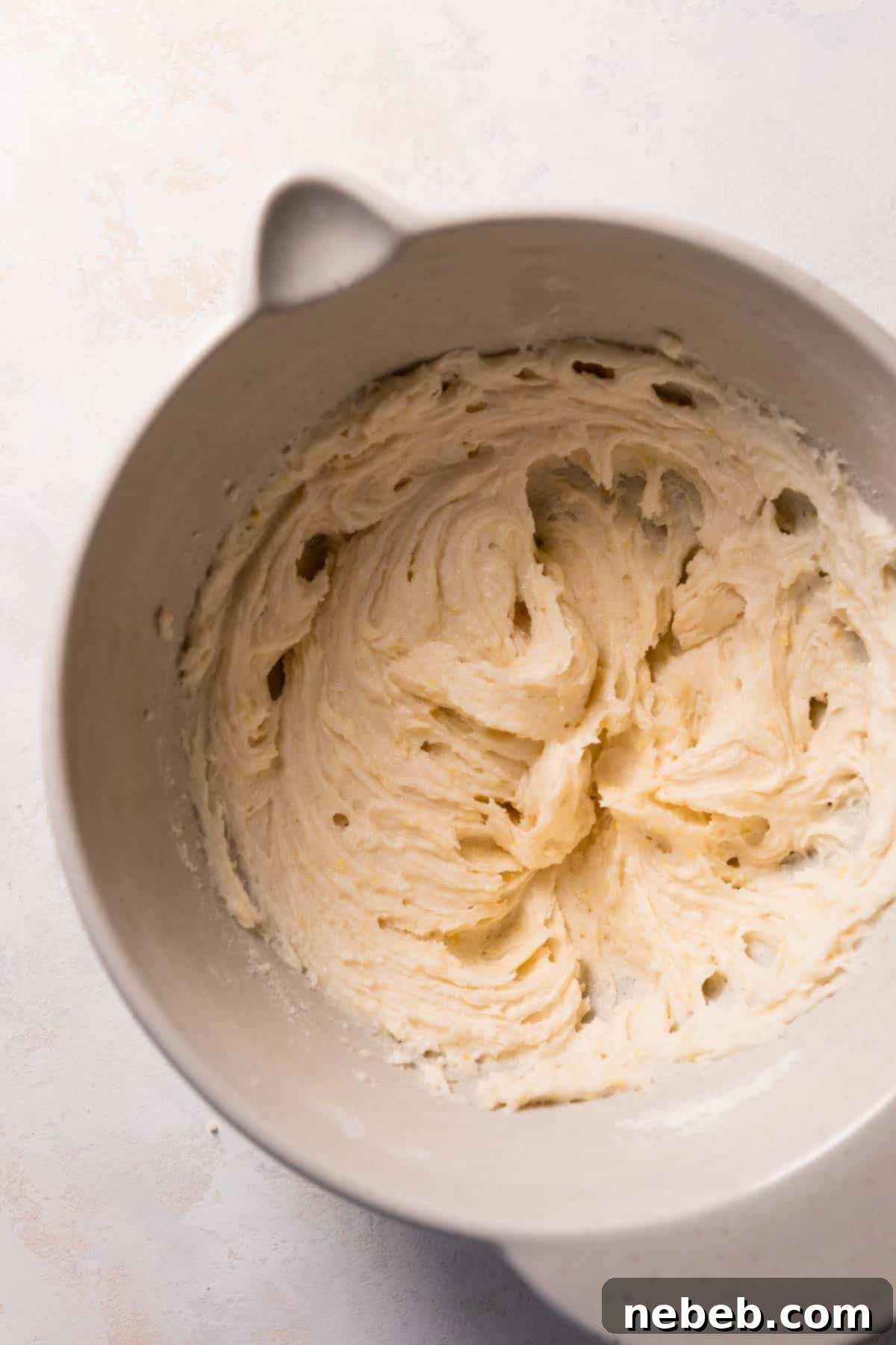 Smooth, pale yellow lemon cake batter in a mixing bowl after the sour cream and oil have been incorporated.