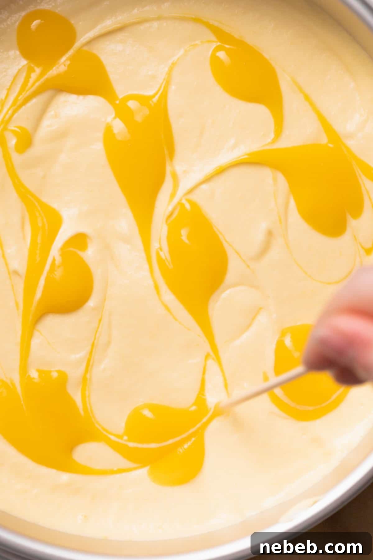 The final step: swirling the remaining mango puree onto the top of the mousse cake for decoration.