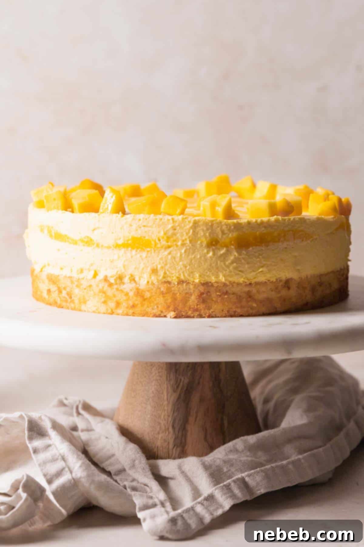 The chilled mango mousse cake, perfectly set and ready to be served on a cake stand.