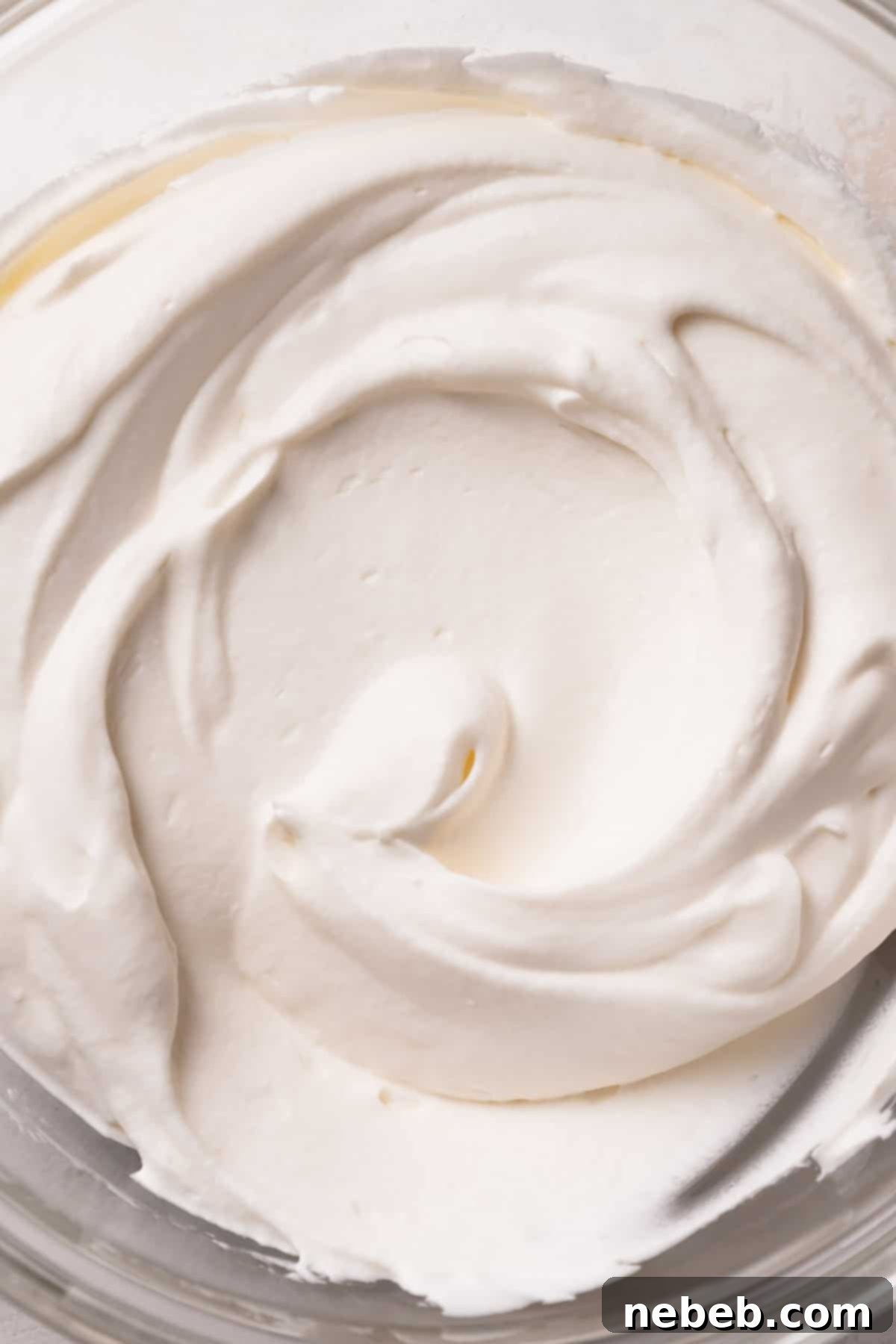 Fluffy whipped cream in a mixing bowl, ready for the mango mousse.