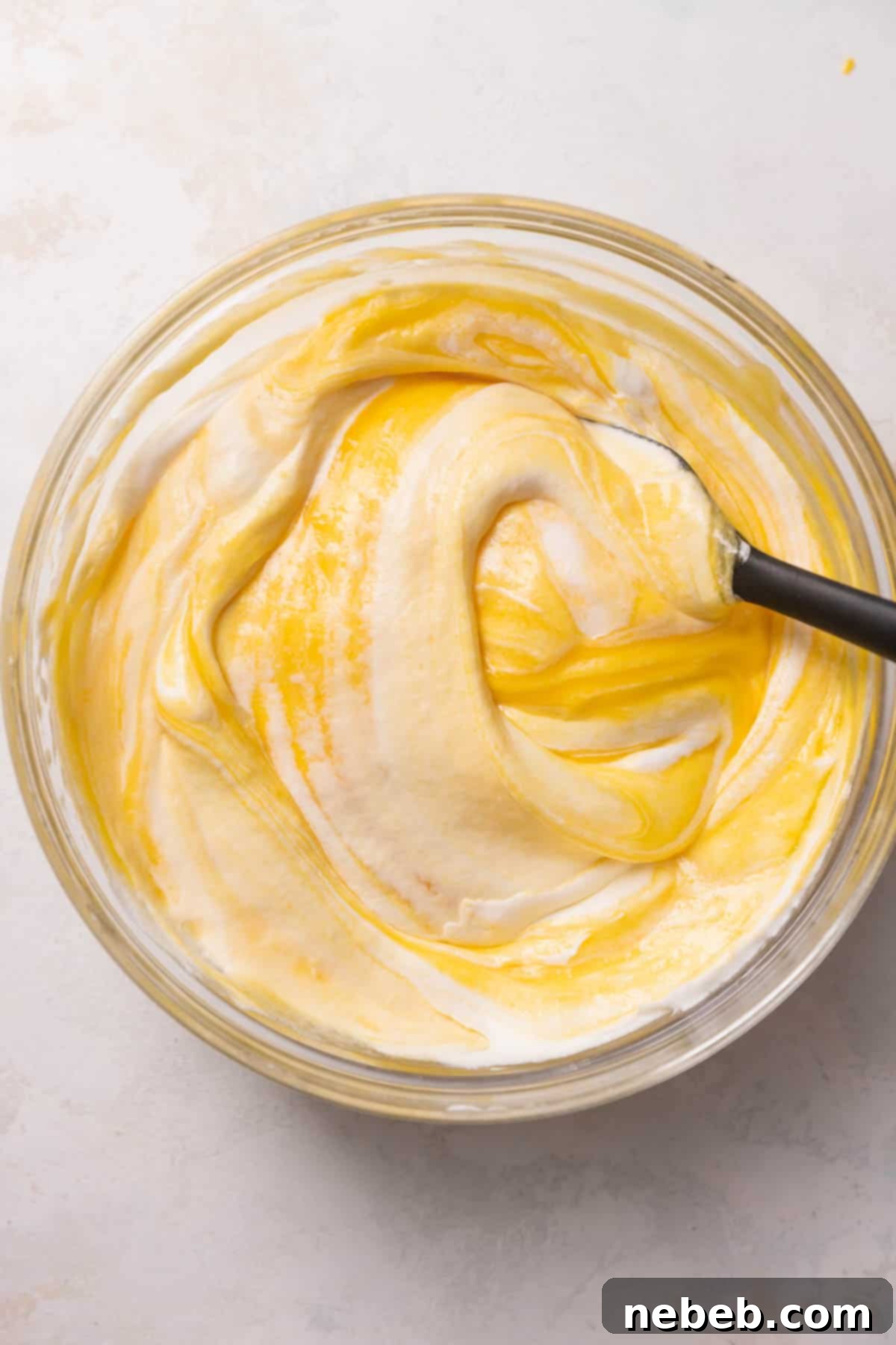 The process of gently folding mango puree into whipped cream to create the mousse.