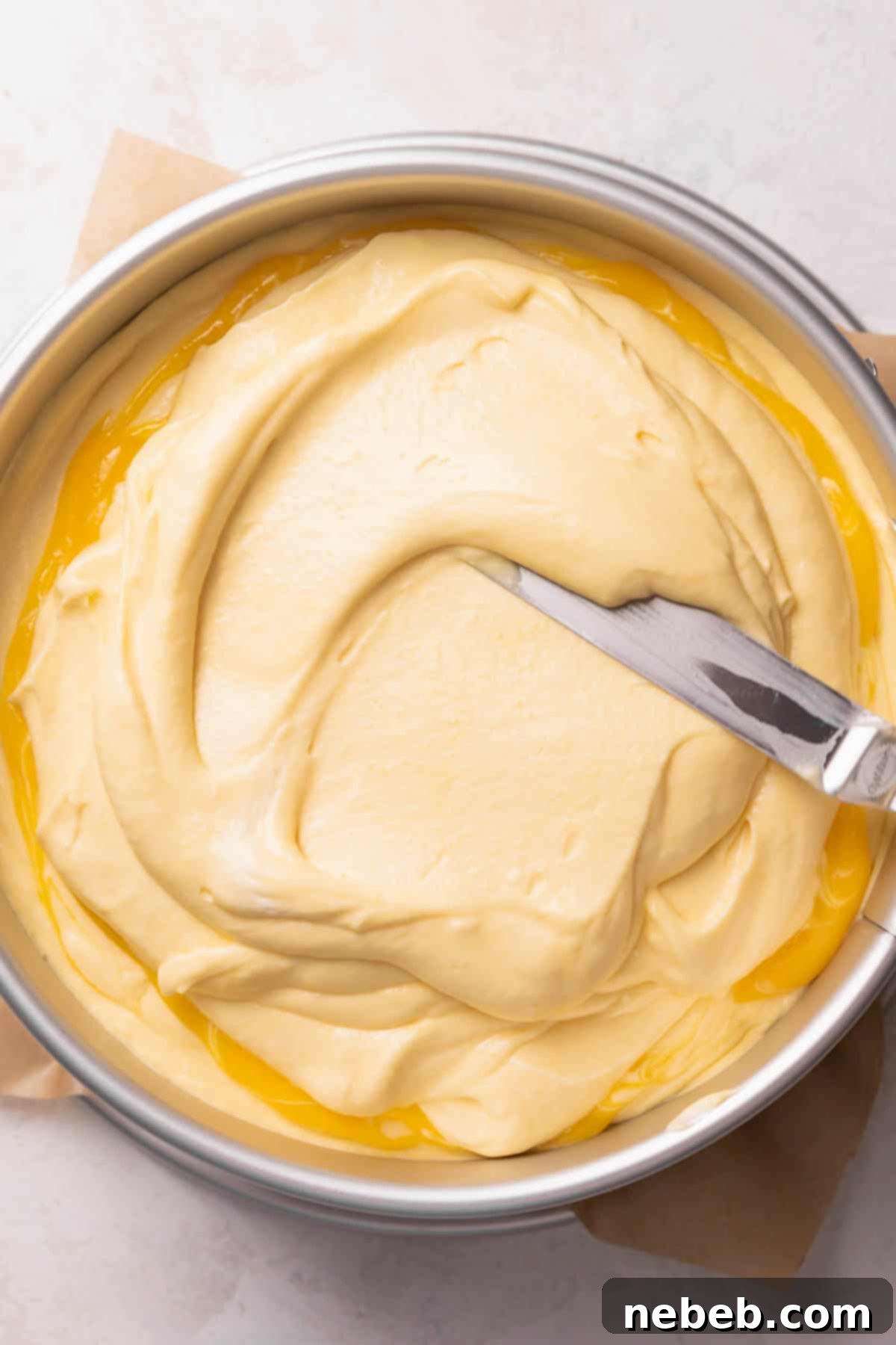 Spreading the first layer of mango mousse evenly on top of the vanilla cake base.