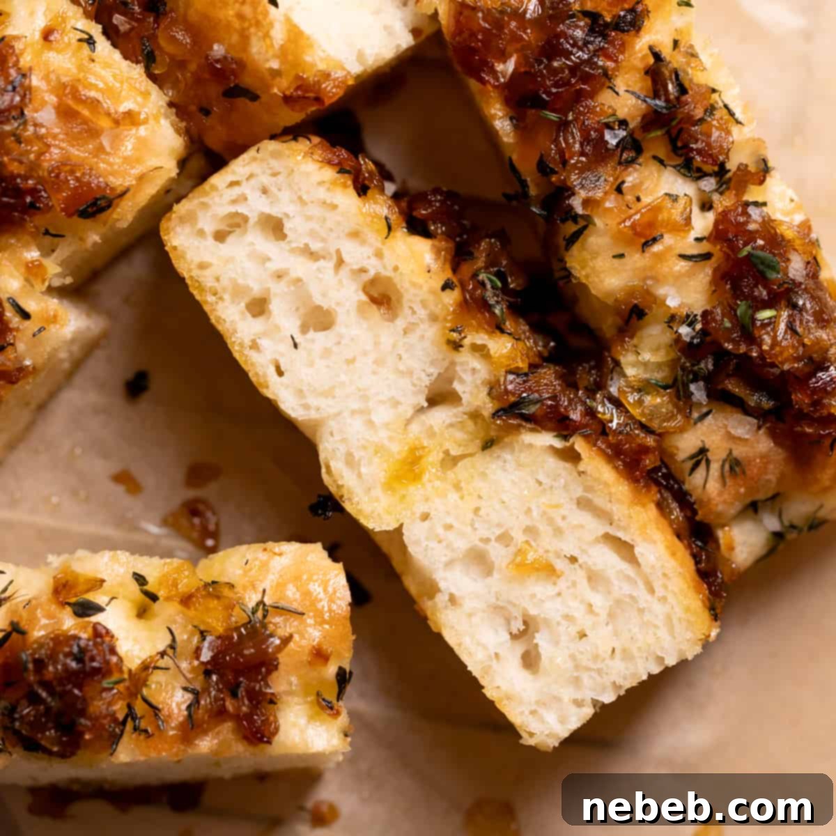Slices of fluffy caramelized onion focaccia on parchment paper, ready to be served.