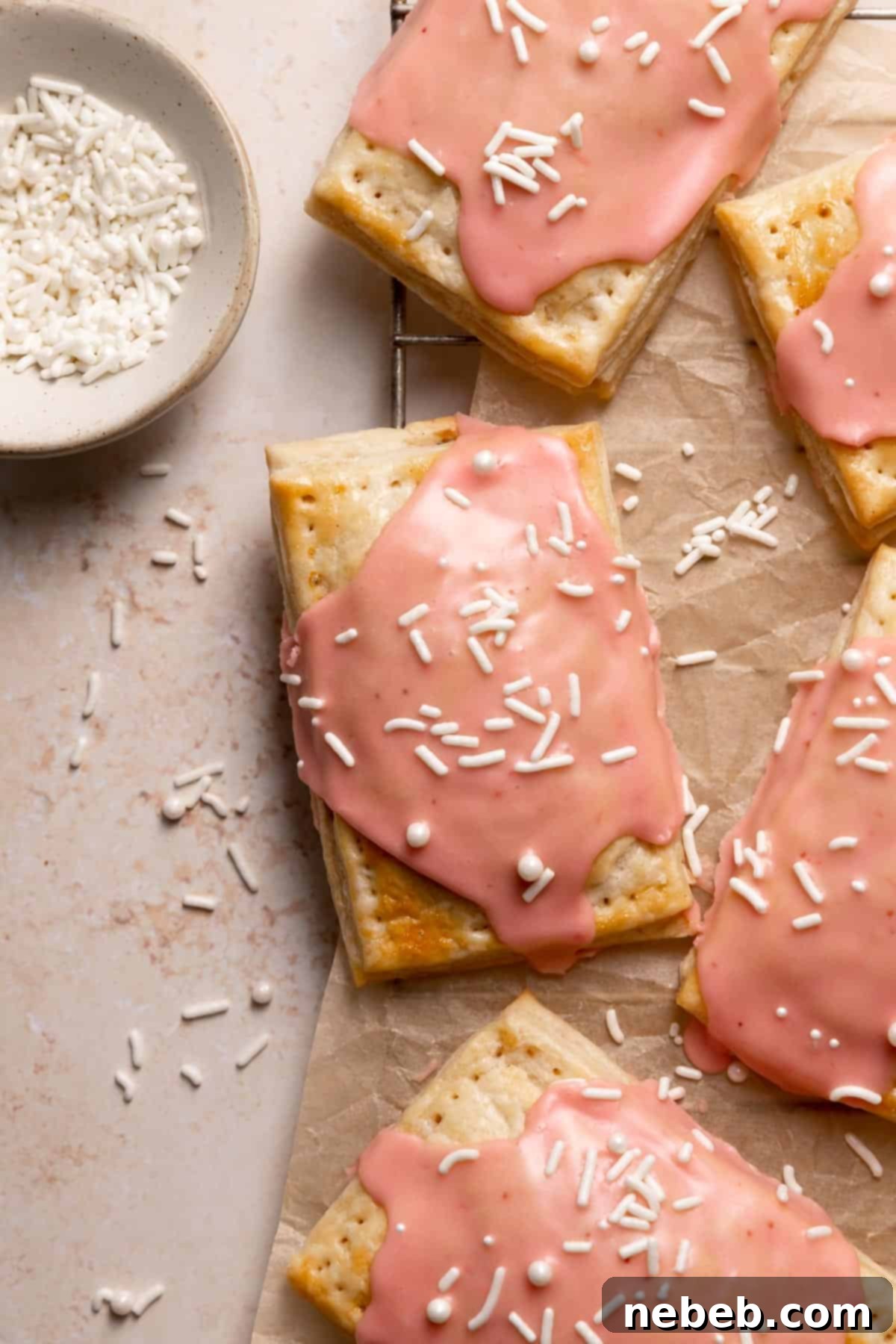 Homemade pop tarts with pink glaze and white sprinkles, showcasing their flaky crust and vibrant filling.