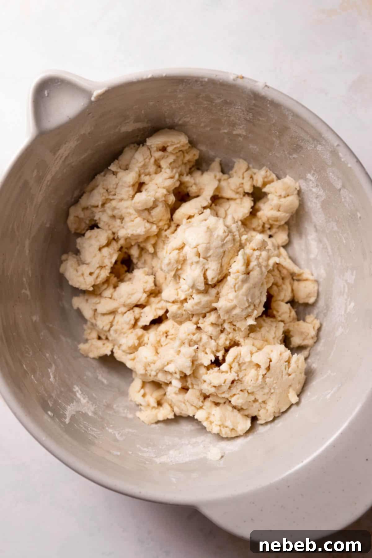 Pie dough coming together in a mixing bowl with a paddle attachment.