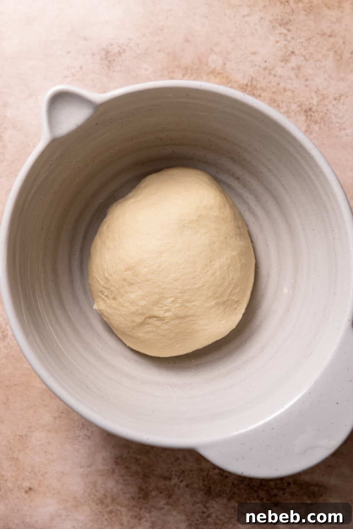 Smooth, soft, and elastic dough resting in a mixing bowl, covered for rising.