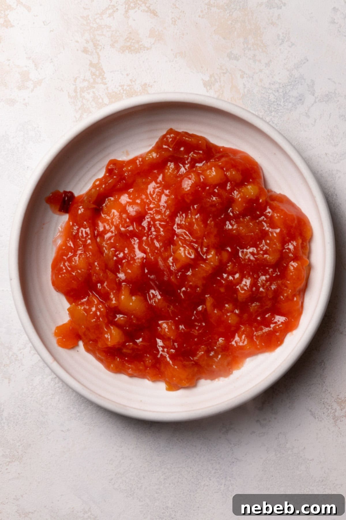 A white bowl filled with homemade fresh peach jam, ready for use.