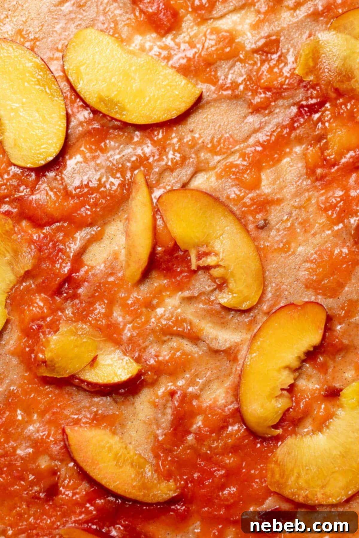Cinnamon roll dough covered with layers of cinnamon sugar, peach jam, and thin peach slices.