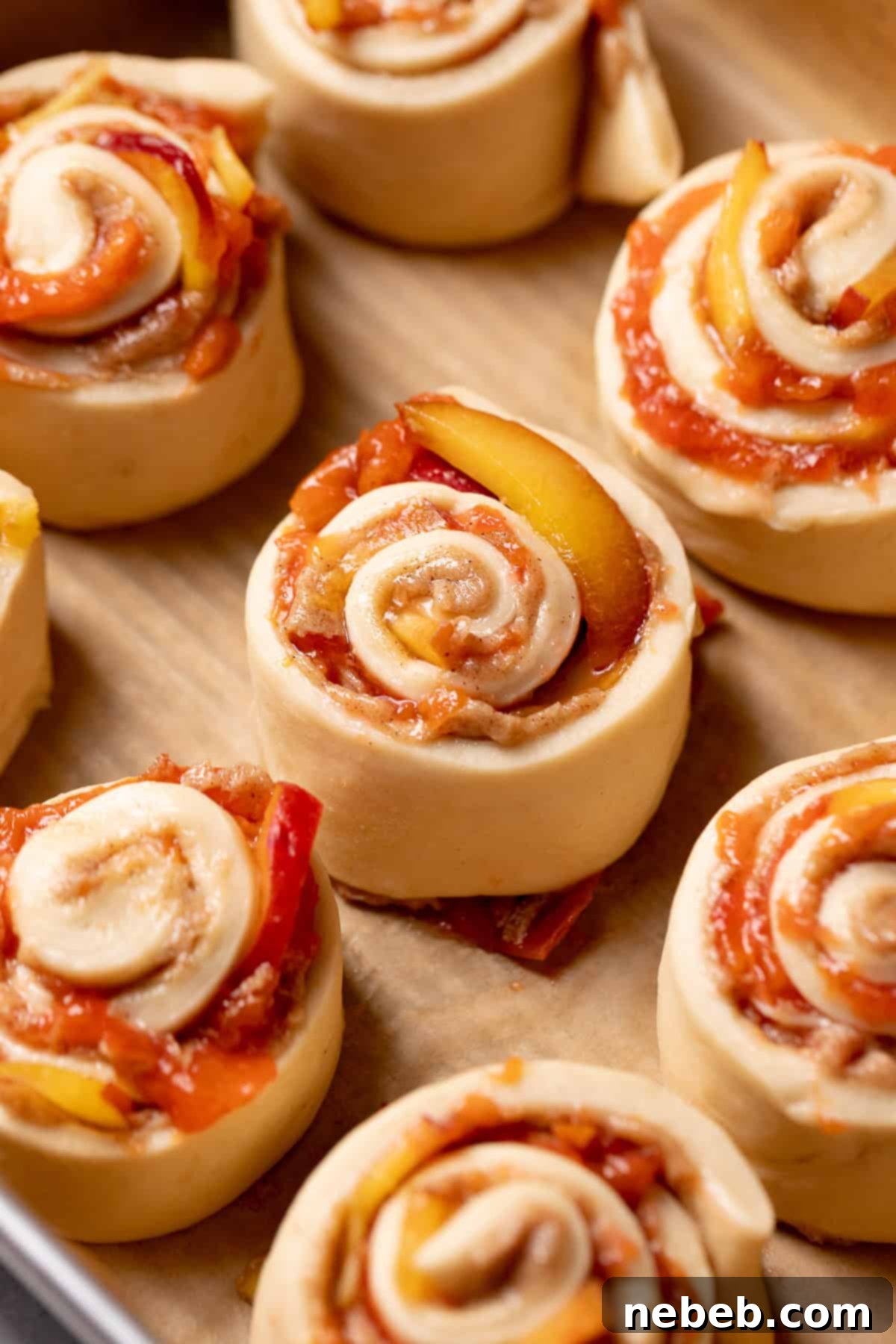 Unbaked peach cobbler cinnamon rolls, cut and placed in a 9x13 baking pan, ready for their second rise.