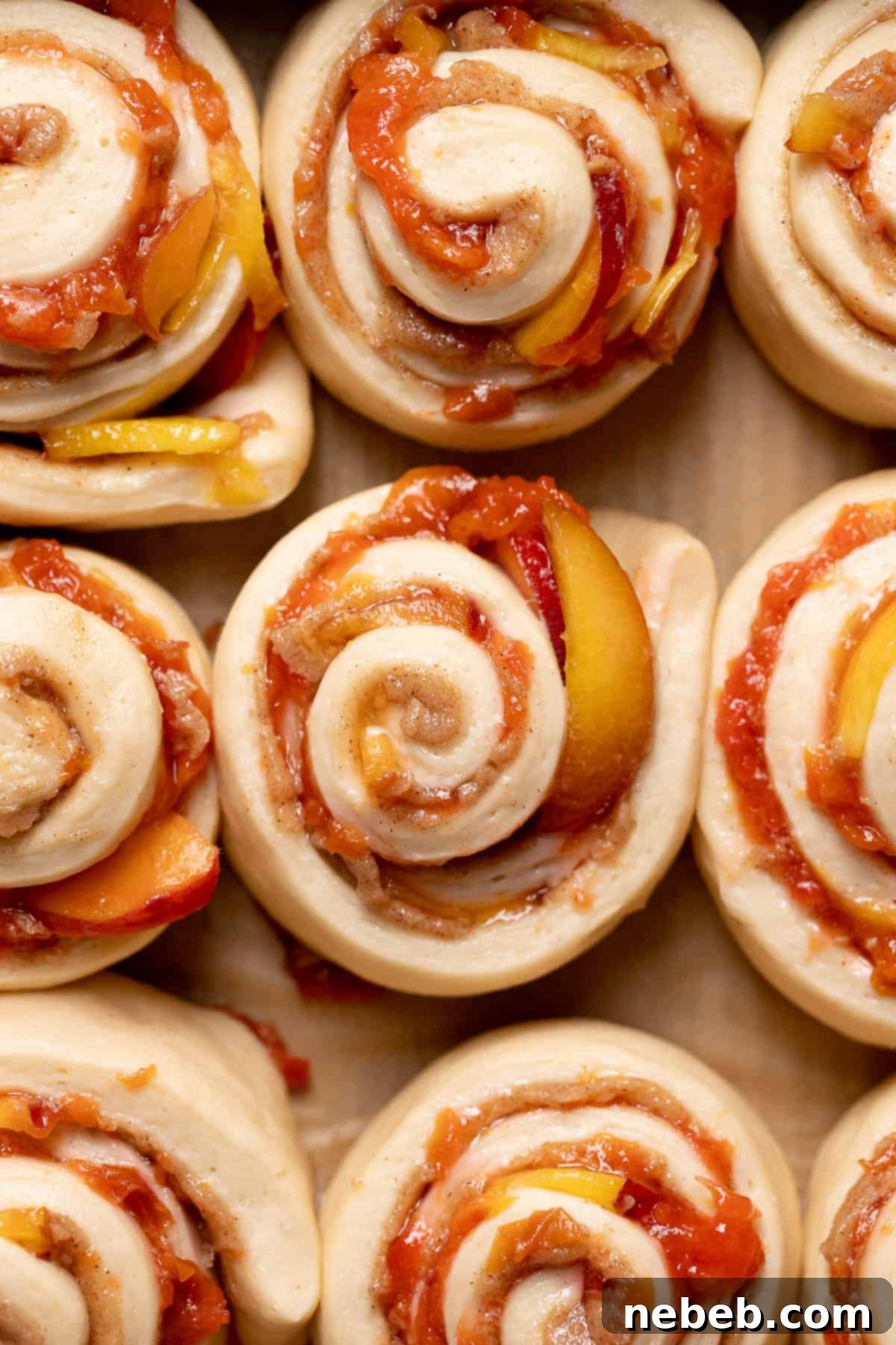 Puffy, risen peach cobbler cinnamon rolls in a baking pan, showing they are ready to bake.