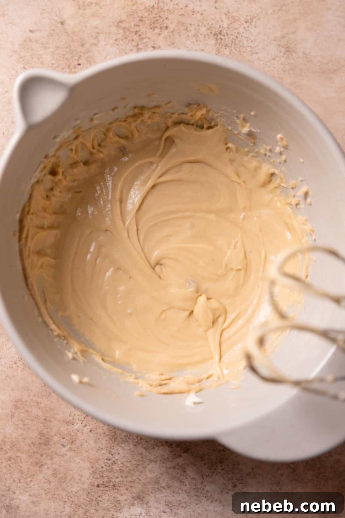 Cookie batter in a bowl after eggs and vanilla have been incorporated, showing a smooth, cohesive mixture.